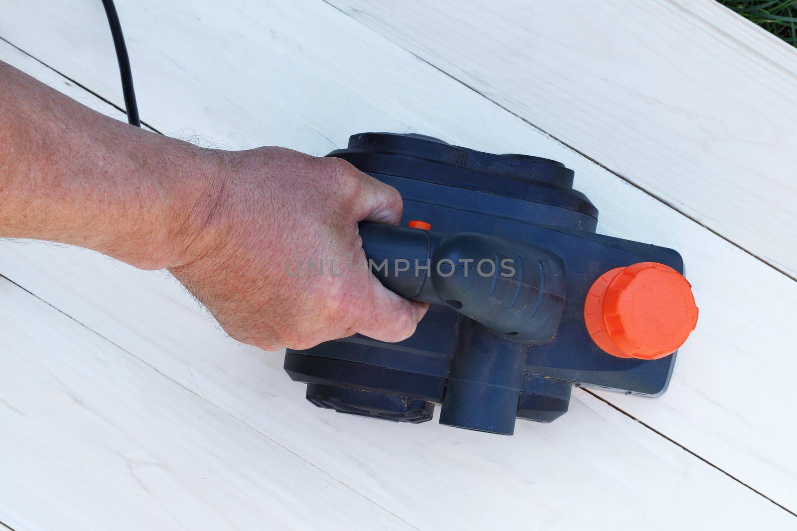 Man sanding wood with orbital sander in workshop