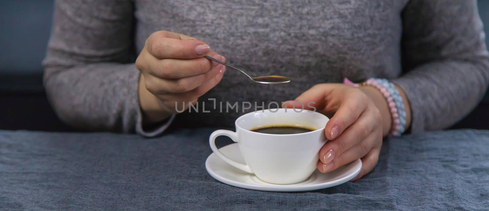 Woman at the table with a cup of coffee. Selective focus. Drink.
