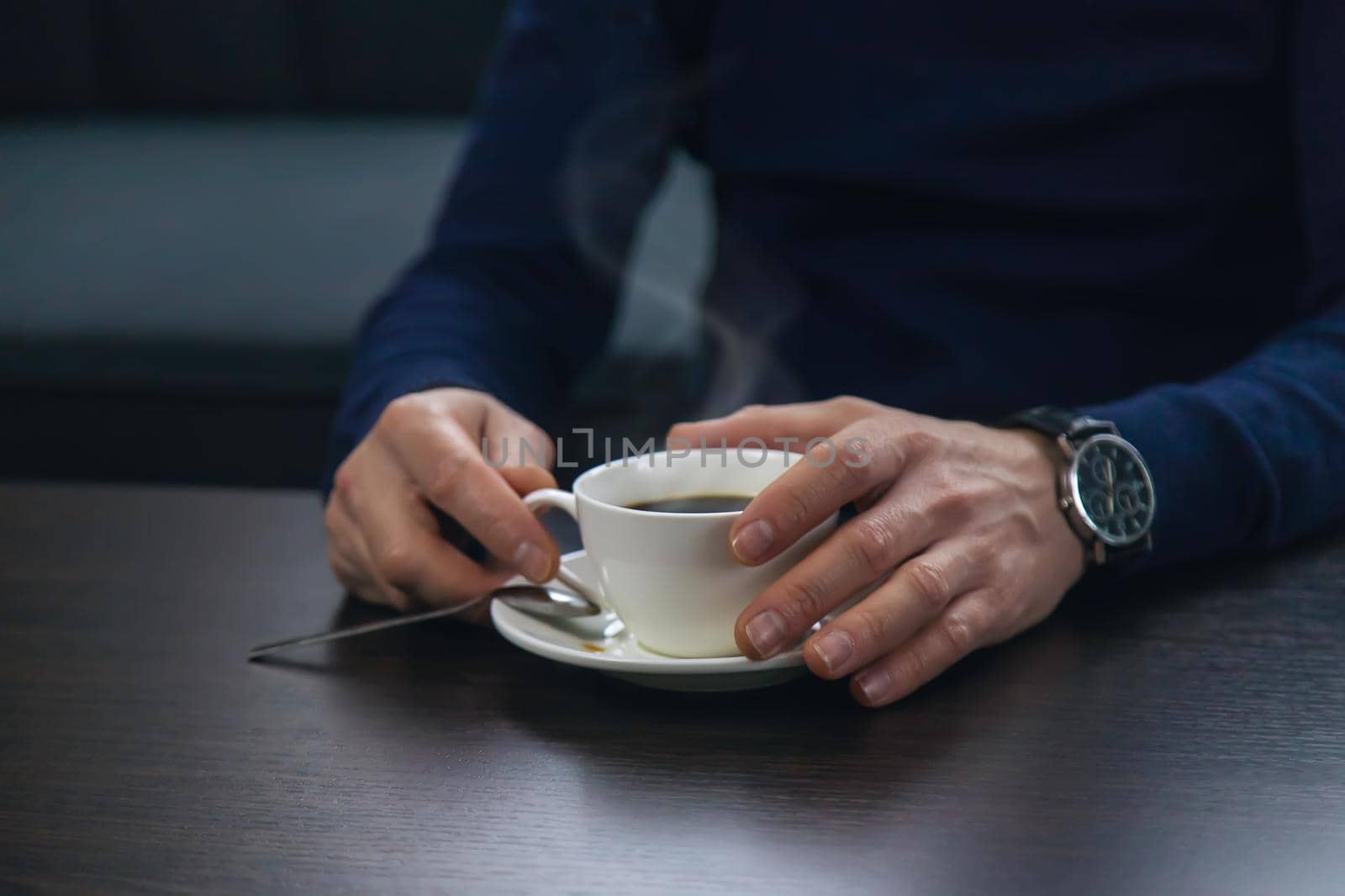 A man at the table with a cup of coffee. Selective focus. Drink.