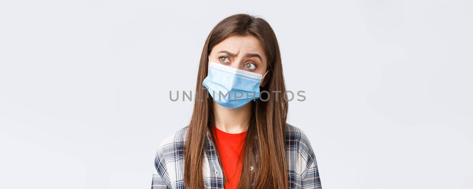 Coronavirus outbreak, leisure on quarantine, social distancing and emotions concept. Thoughtful and intrigued woman in medical mask, looking left with interest, thinking, white background by Benzoix