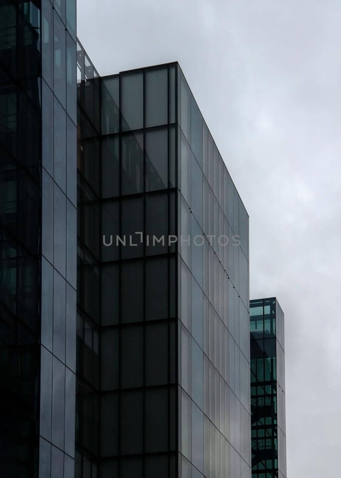 London, United Kingdom - October 22, 2006: Rectangle windows on glass and steel offices ("More London Estates" design by Foster and Partners) overcast sky in background. by Ivanko