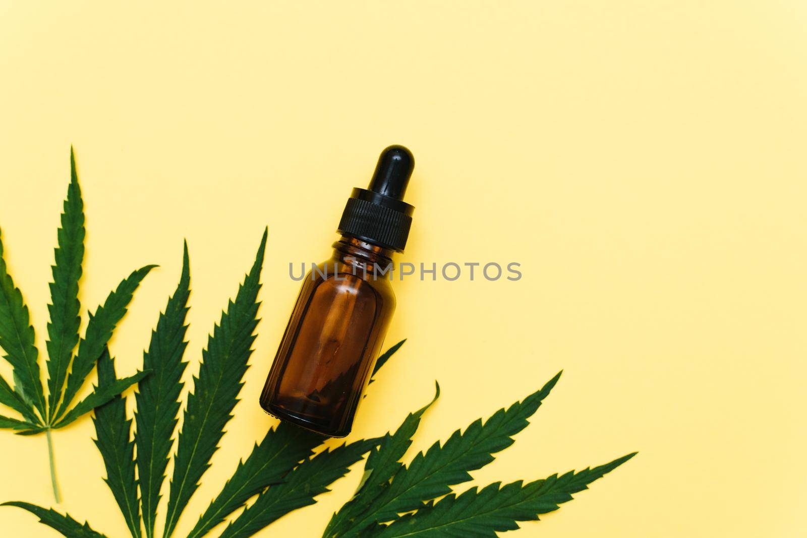 Hemp oil on a yellow background with copy space. Serum with cannabis extract. Natural skin care