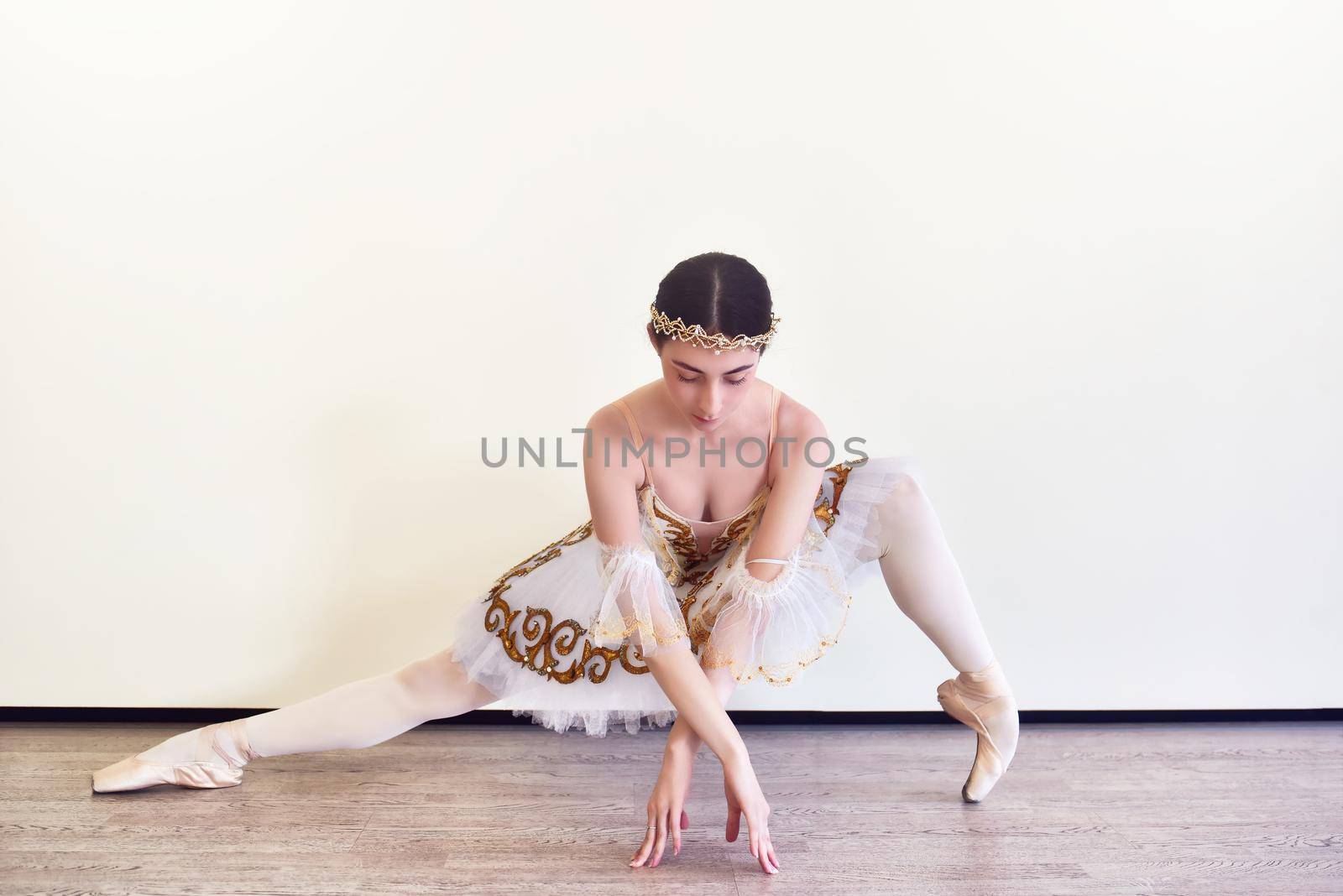 Elegant young Ballerina in white tutu practicing ballet positions in the studio