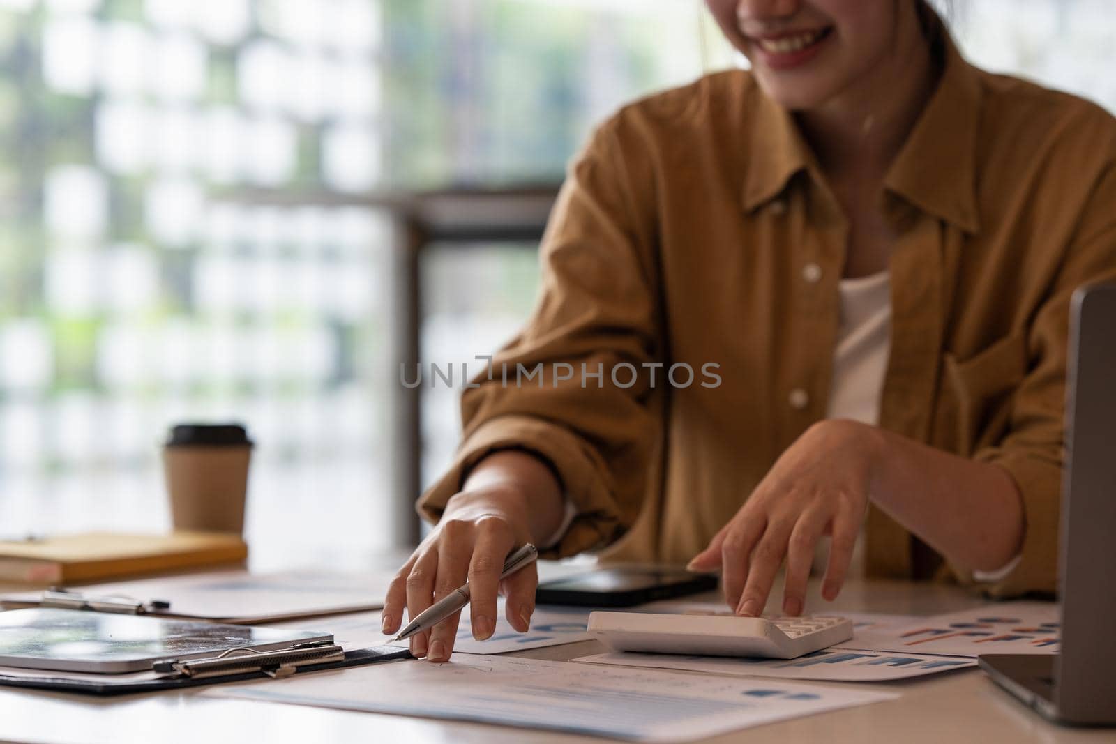 Close up Business woman hand using calculator to calculate the company's financial results and budget. Account Audit Concept. by itchaznong