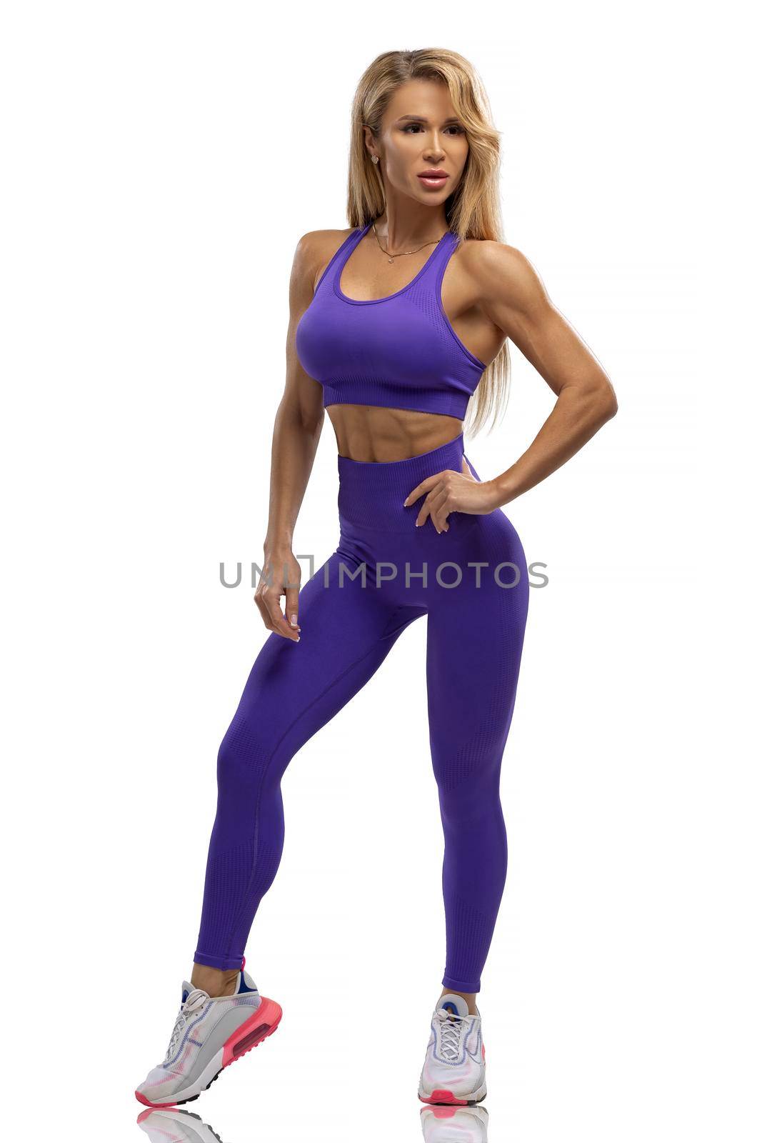 Blonde fit girl in blue leggings and top on a white background in the studio by but_photo