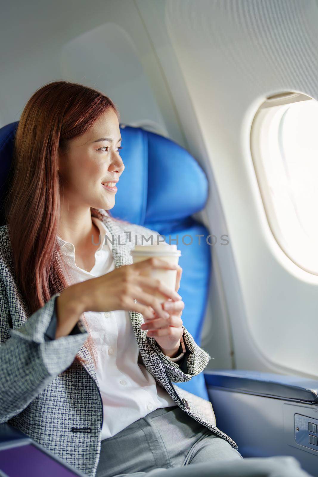 portrait of A successful asian business woman or female entrepreneur in formal suit in a plane sits in a business class seat and drink coffee during flight, relax concept.