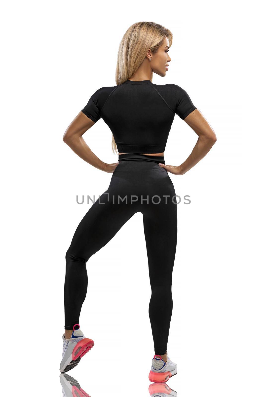 Blonde fit girl in black leggings and top on a white background in the studio by but_photo