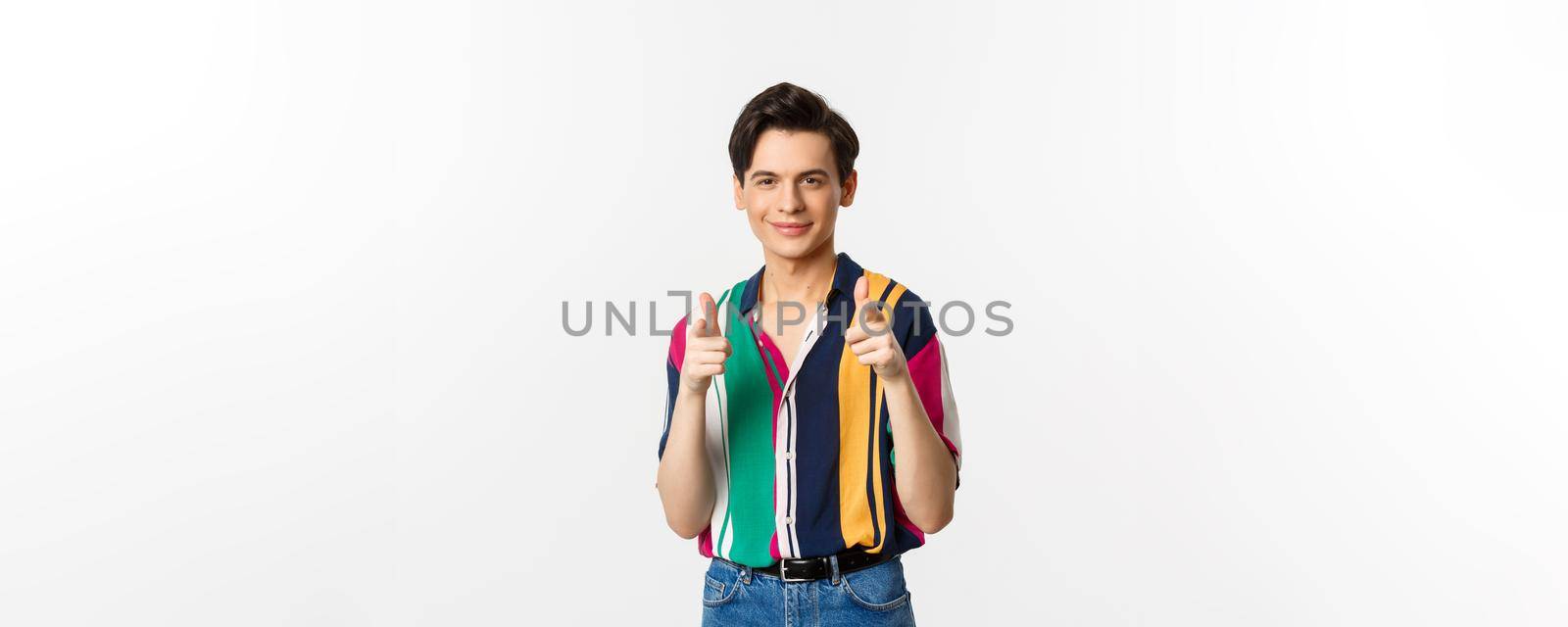 Confident handsome man encourage you, pointing fingers at camera and smiling, being supportive, standing over white background by Benzoix