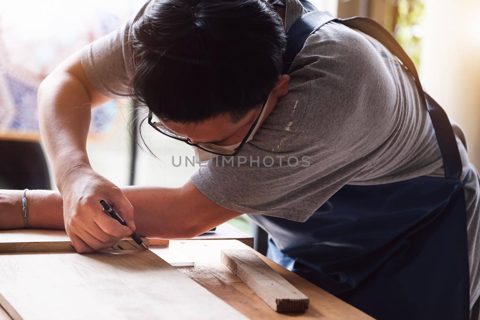 A carpenter measures the planks to assemble the parts, and build a wooden table for the customer