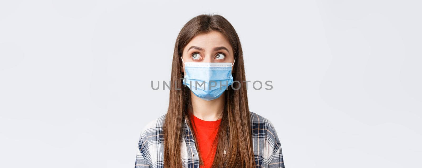 Coronavirus outbreak, leisure on quarantine, social distancing and emotions concept. Close-up of thoughtful, young woman in medical mask, look upper left corner reading sign or have bubble thought by Benzoix