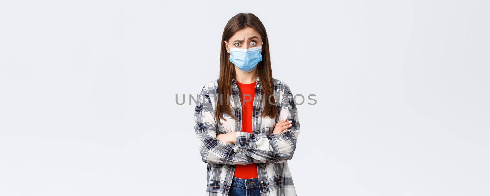 Coronavirus outbreak, leisure on quarantine, social distancing and emotions concept. Shocked and confused young pretty teenage girl hear strange news, raise eyebrows puzzled, wear medical mask.