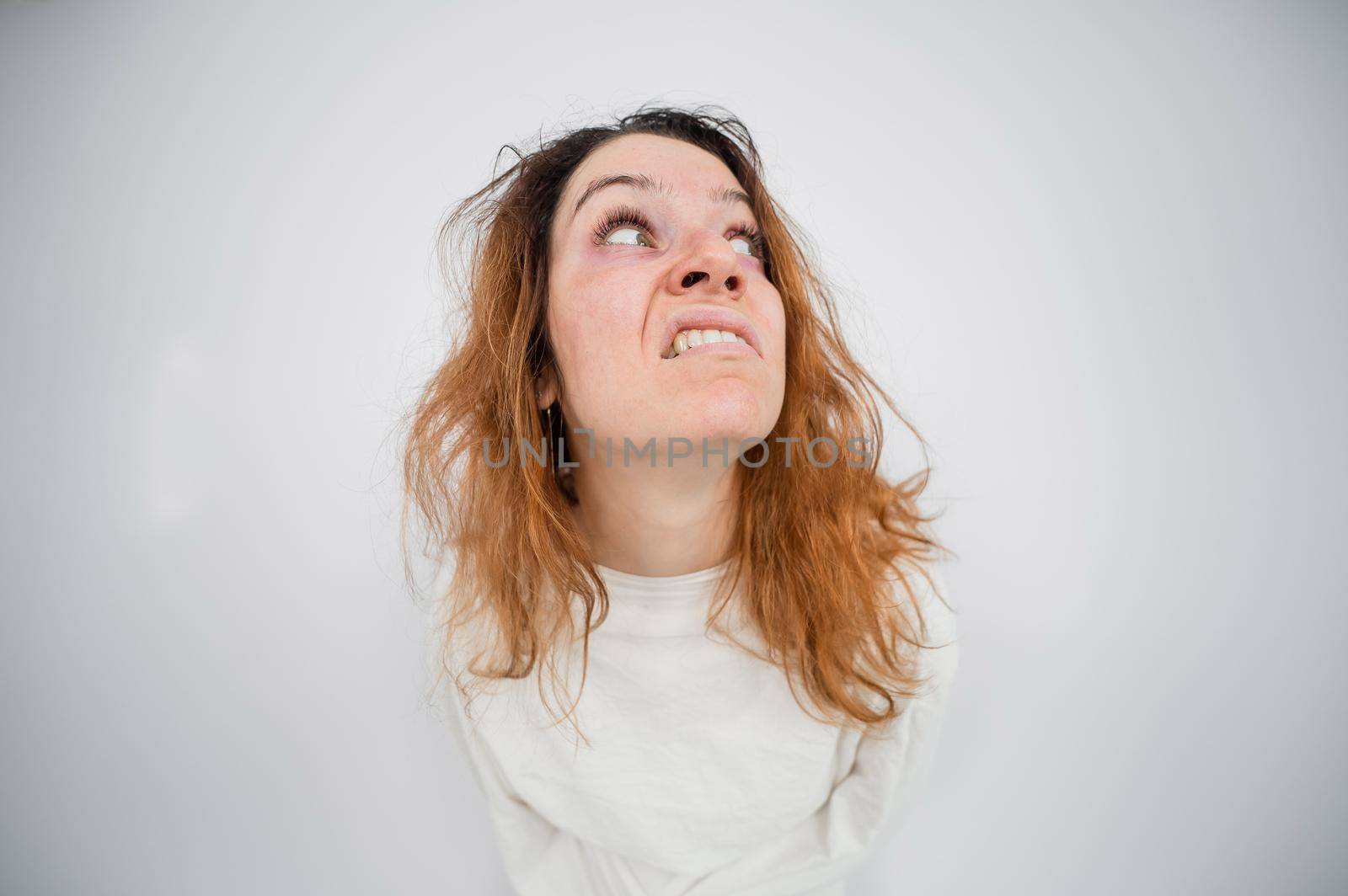 Close-up portrait of insane woman in straitjacket on white background