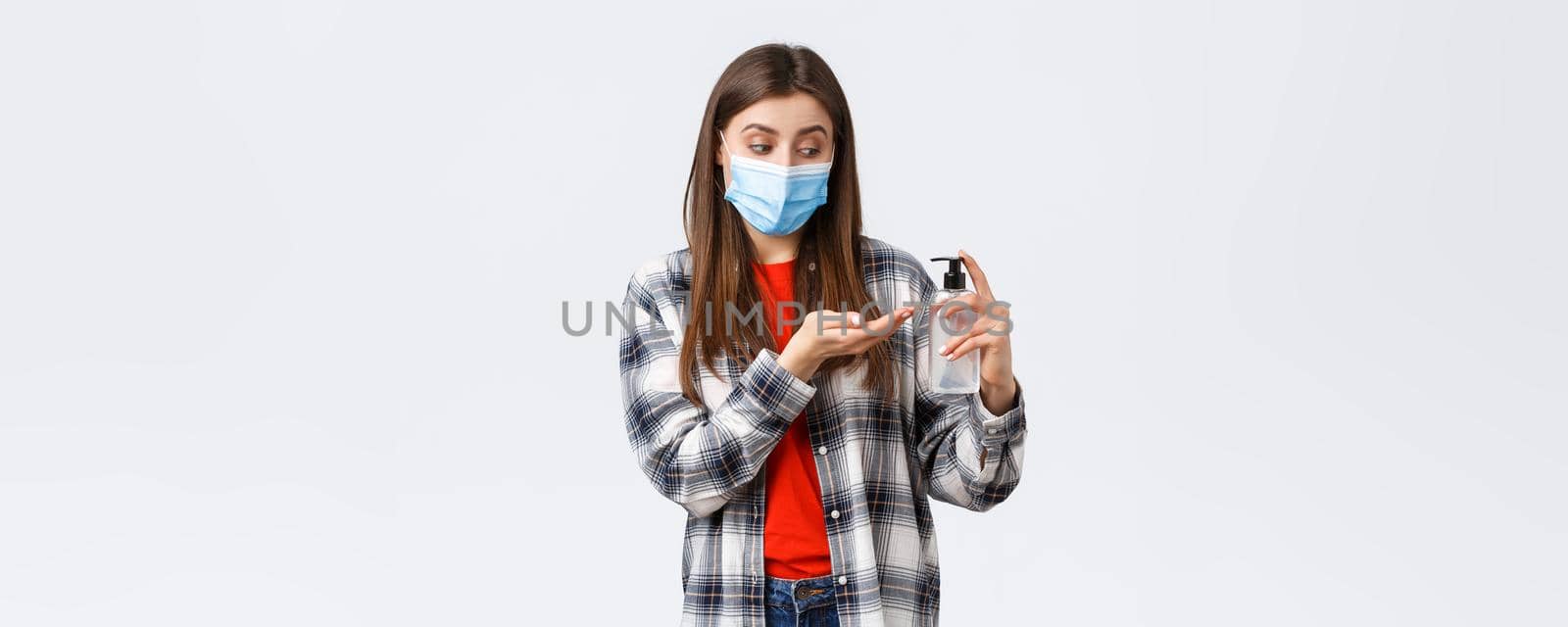 Coronavirus outbreak, leisure on quarantine, social distancing and emotions concept. Cute woman taking care of health doing preventing measures, apply hand sanitizer, wear medical mask by Benzoix