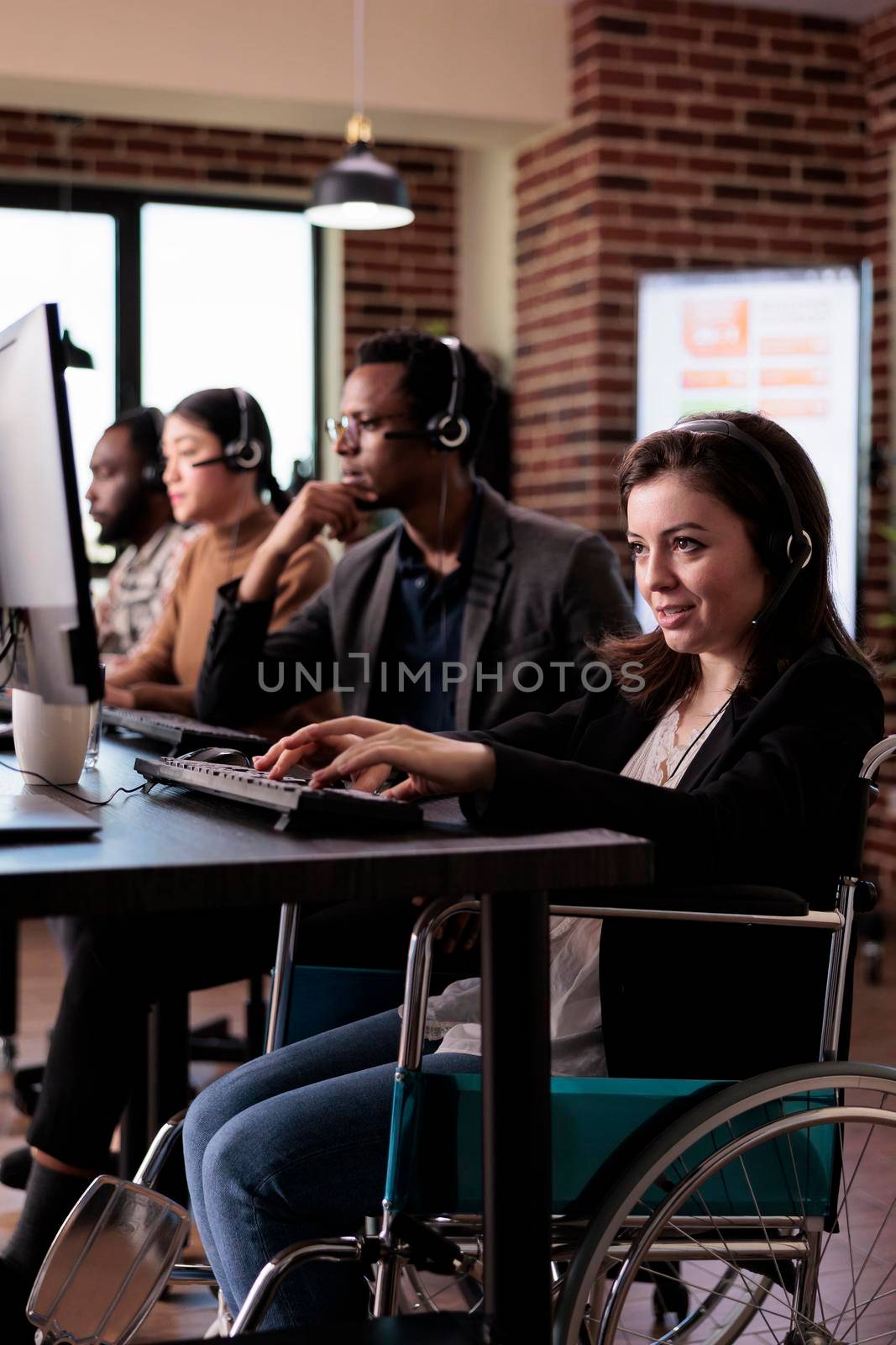 Woman living with disability answering call at customer care service, wheelchair user with physical health condition working at helpline support. Helpdesk operator with chronic pain.