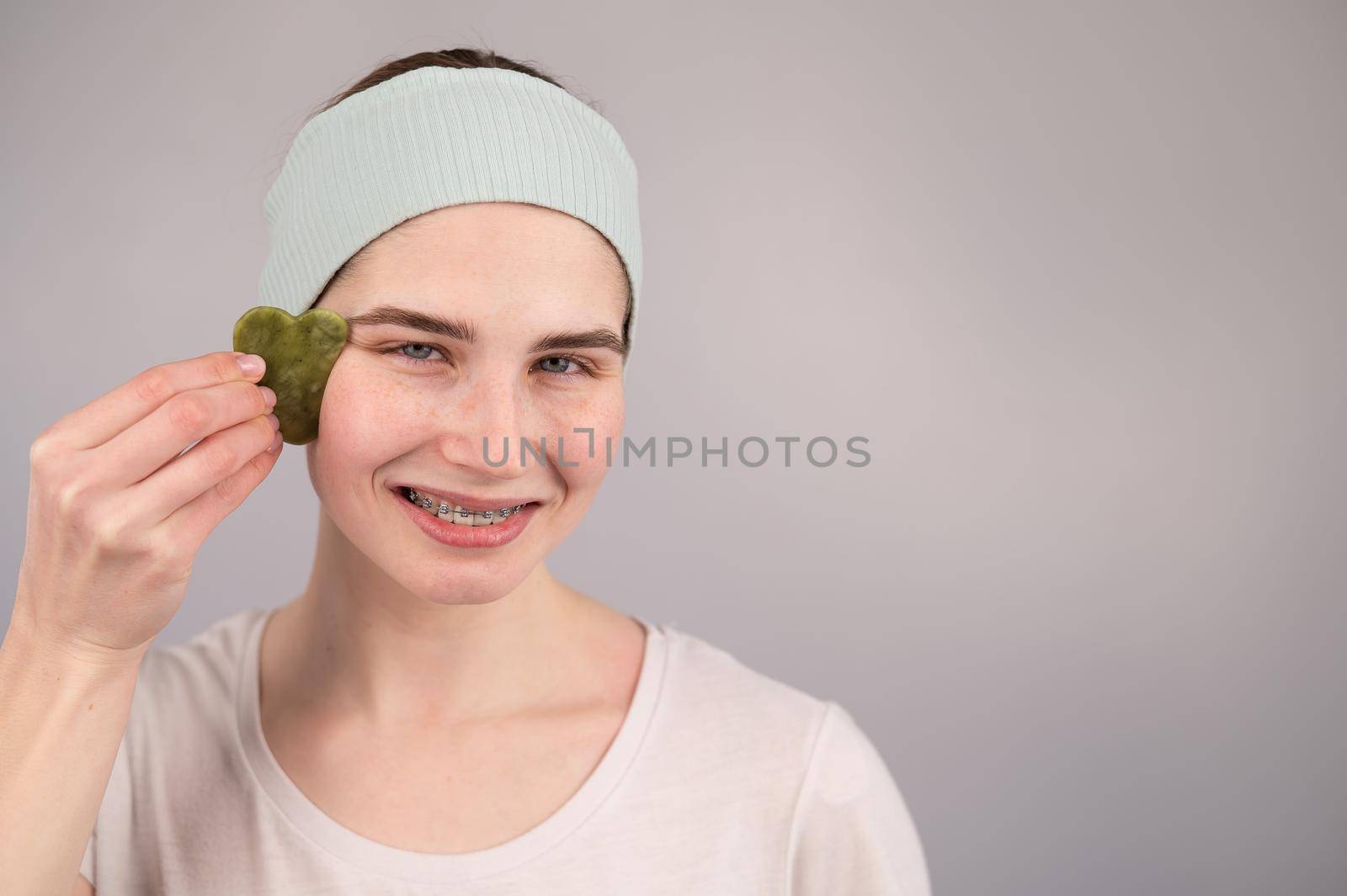 Close-up portrait of a smiling woman with braces doing home care with a gouache massager