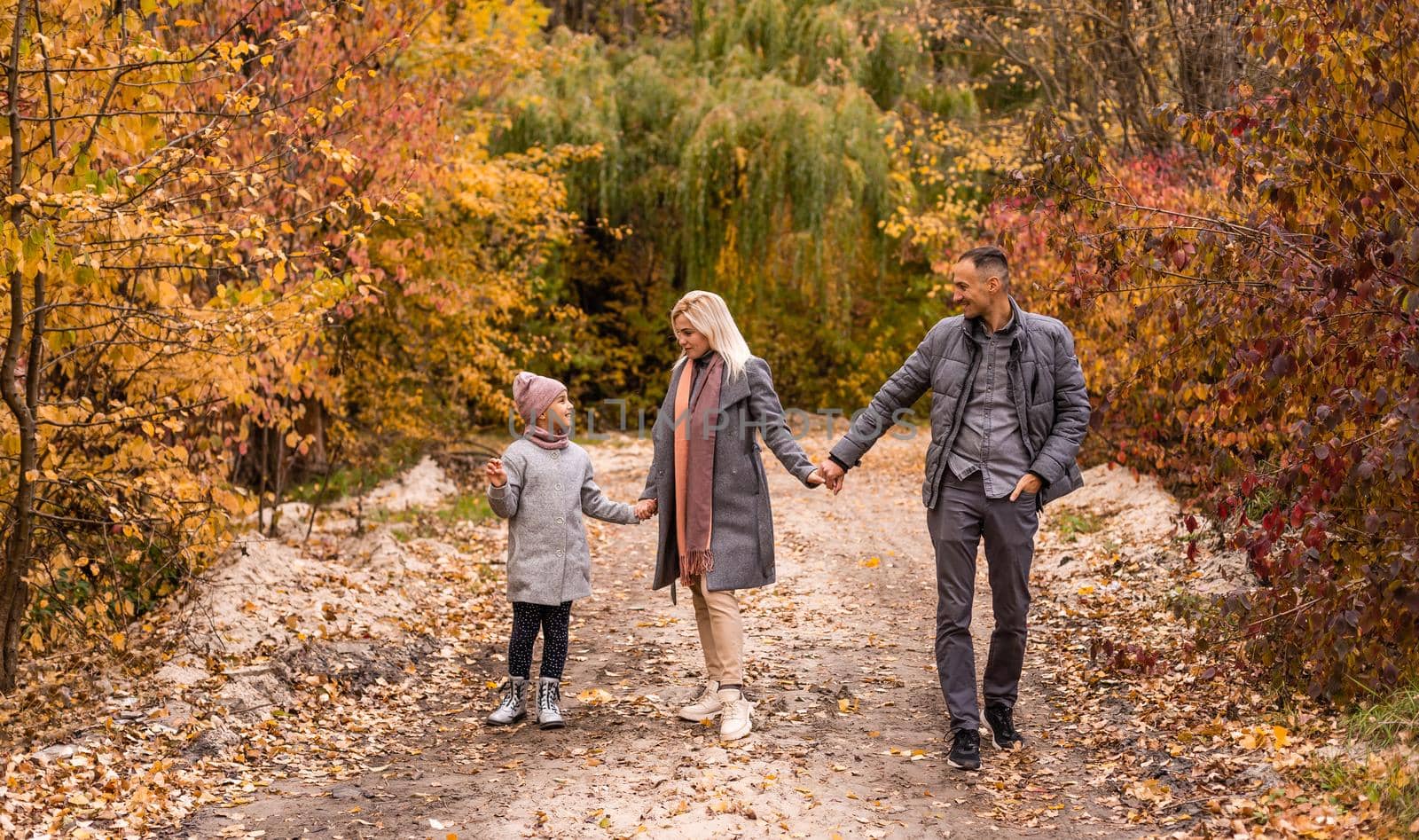 A Family of four enjoying golden leaves in autumn park.