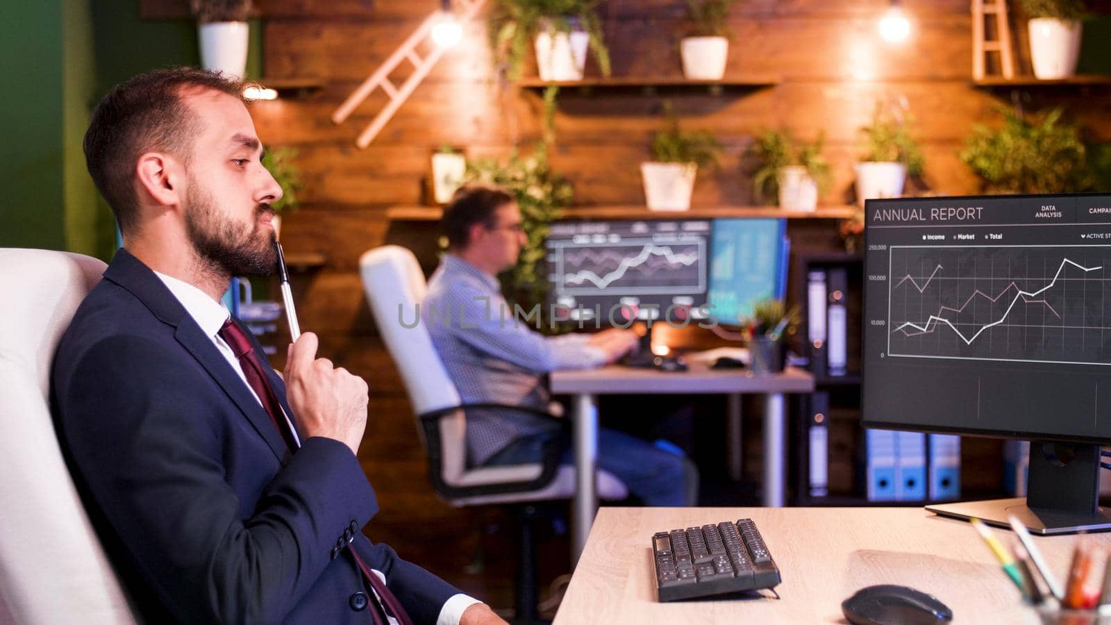 Businessman thinking in front of his monitors in the office by DCStudio