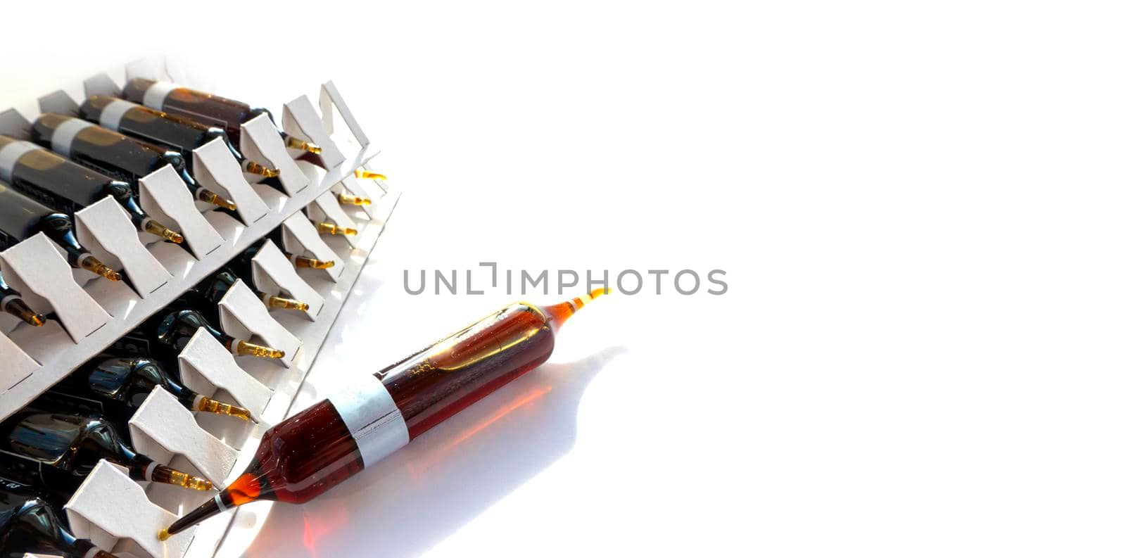 Group object of liquid medicinal agent in limpid glassware in medical laboratory. Group of ampoules with a transparent medicine in medical laboratory. horizontal perspective view of many brown ampoules set in pharmaceutical packaging white container