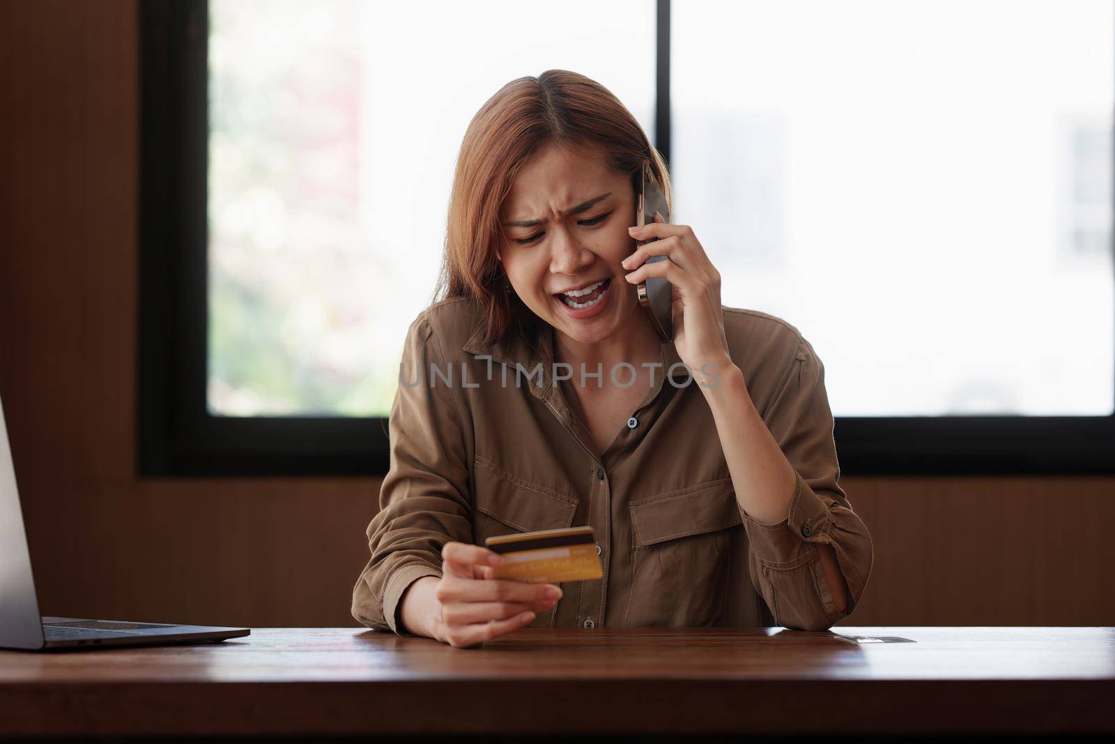 A stressed woman while talking with credit card operator. Online payment concept. by itchaznong