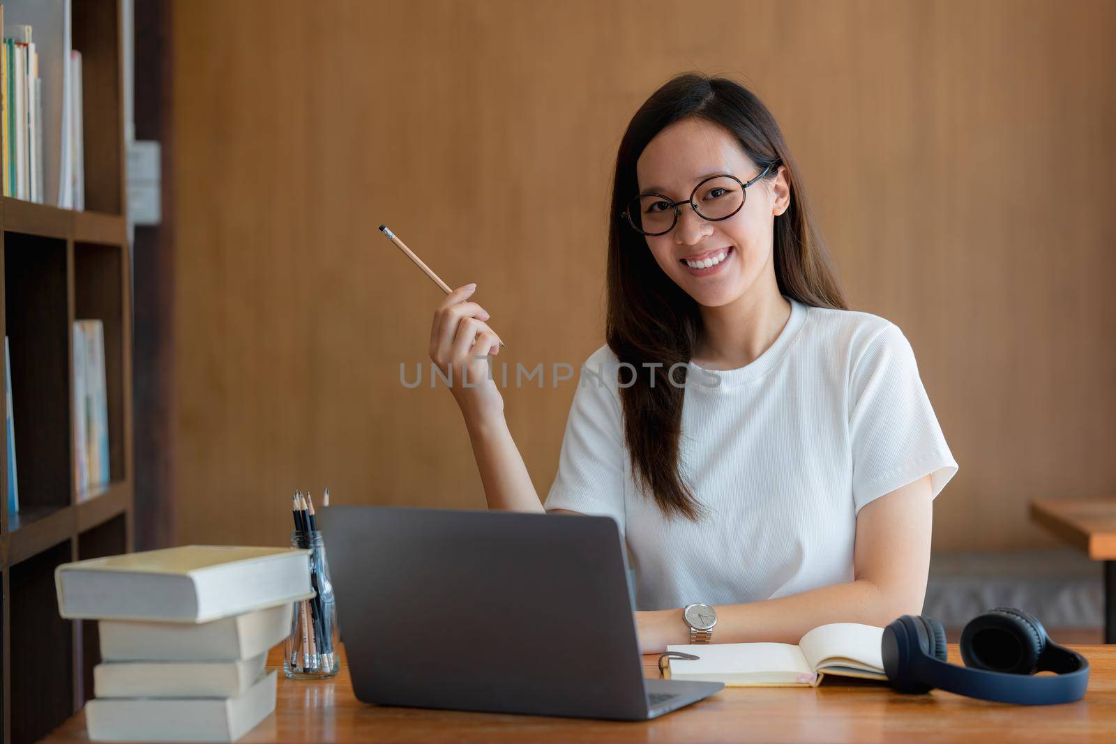 Image of Young woman with a headset working online on laptop computer. studying or working from home online concept. by itchaznong