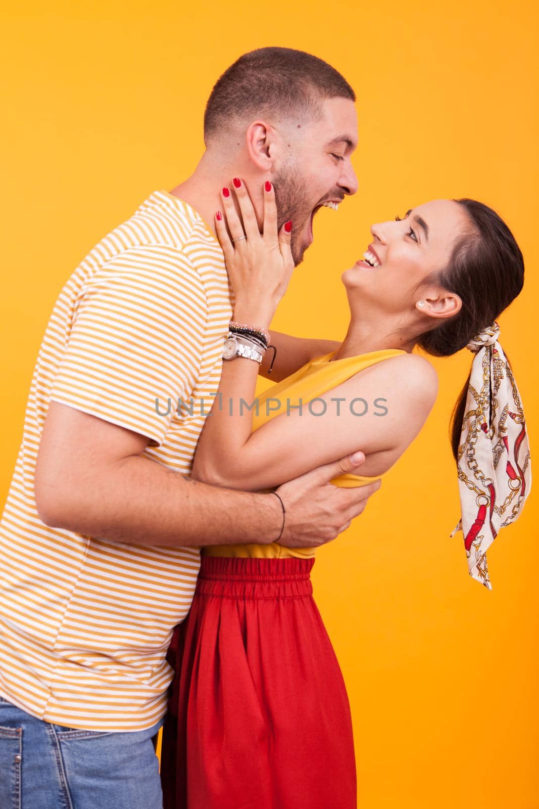 Cheerful young couple in studio over yellow background by DCStudio