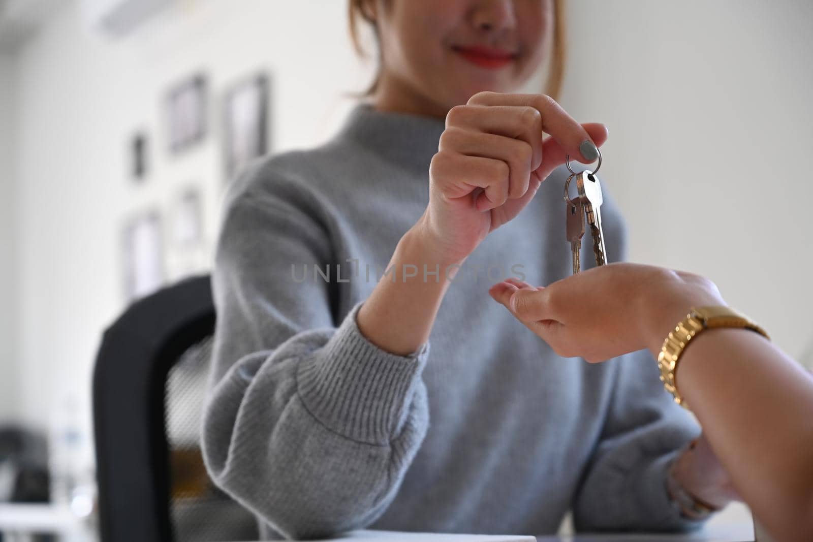 Smiling female estate agent giving house keys to customer. Real estate investment concept.