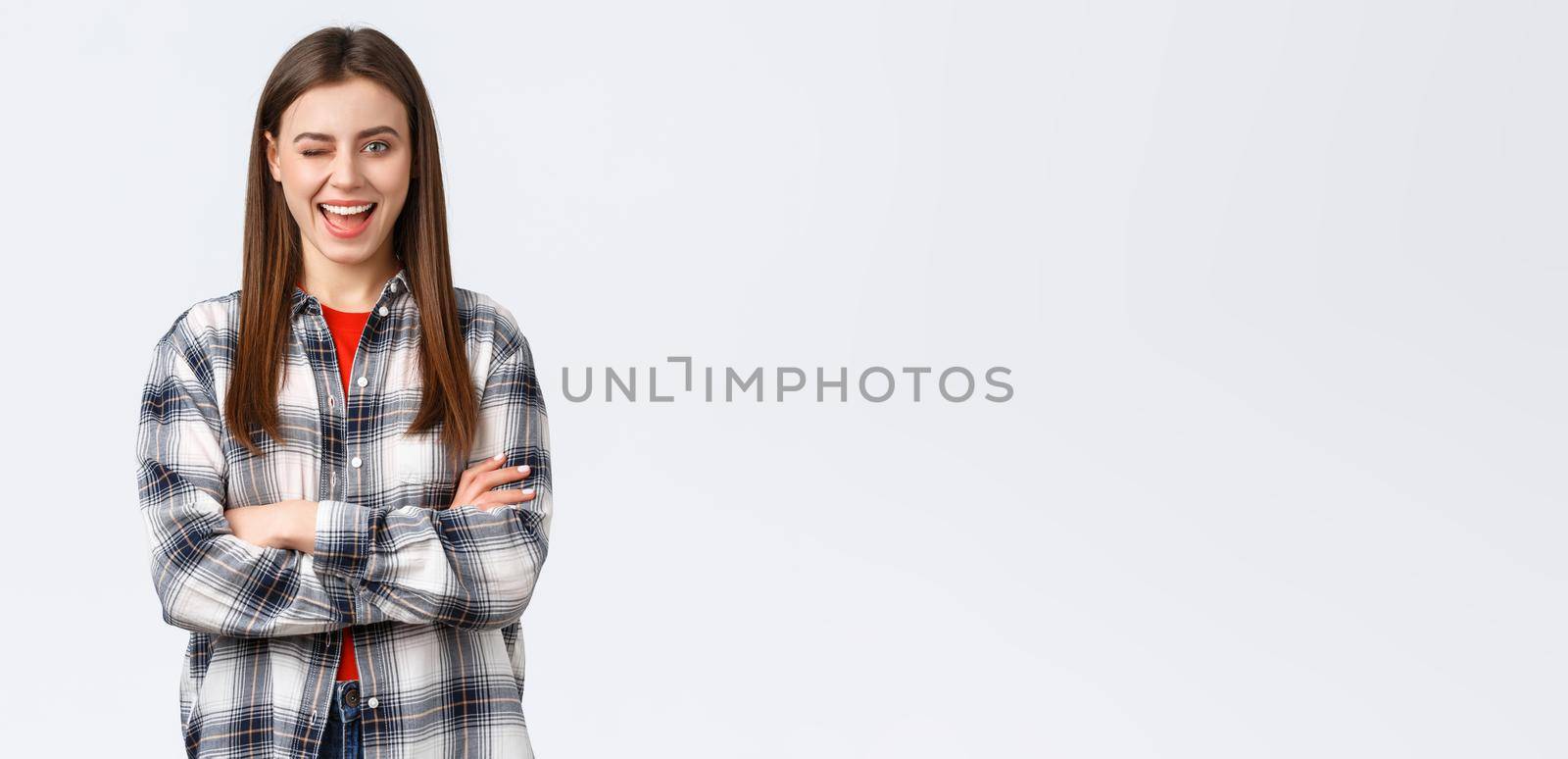 Lifestyle, different emotions, leisure activities concept. Enthusiastic and confident attractive woman, female student in checked casual shirt winking excited and smiling, cross arms chest ready by Benzoix