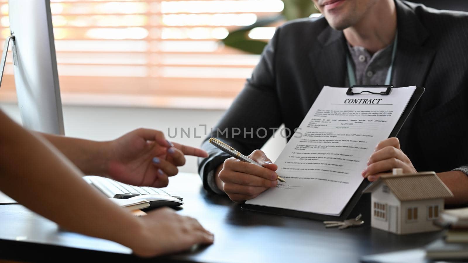 Cropped shot male financial advisor consulting with clients about new house and showing contract document.