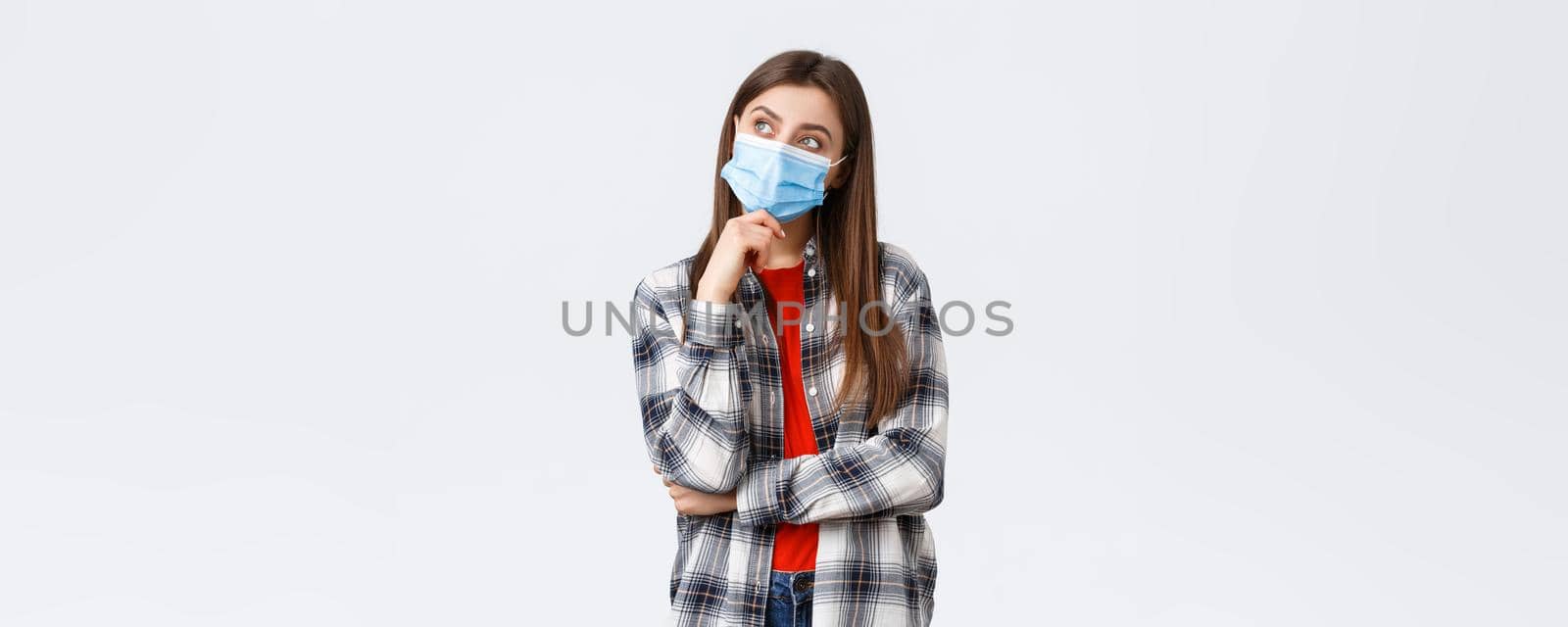 Coronavirus outbreak, leisure on quarantine, social distancing and emotions concept. Dreamy and thoughtful beautiful girl in medical mask, imaging something, thinking as look upper left corner by Benzoix