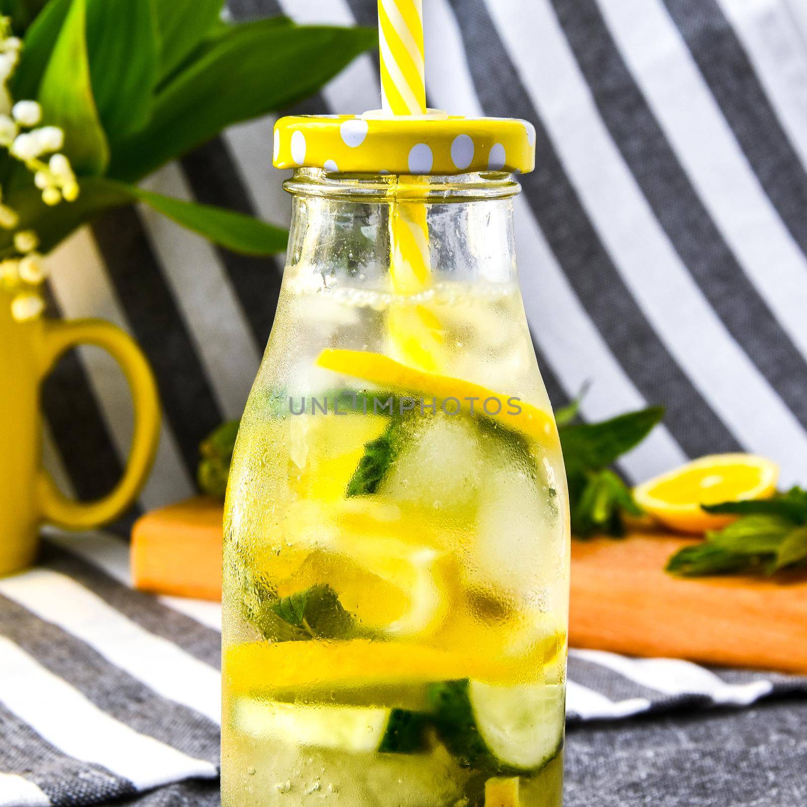 Lemonade, mojito with cutted lemon and cucumber, mint leaves on cutting board, Summer refreshing detox drinks, selective focus, bouquet lily of the valley