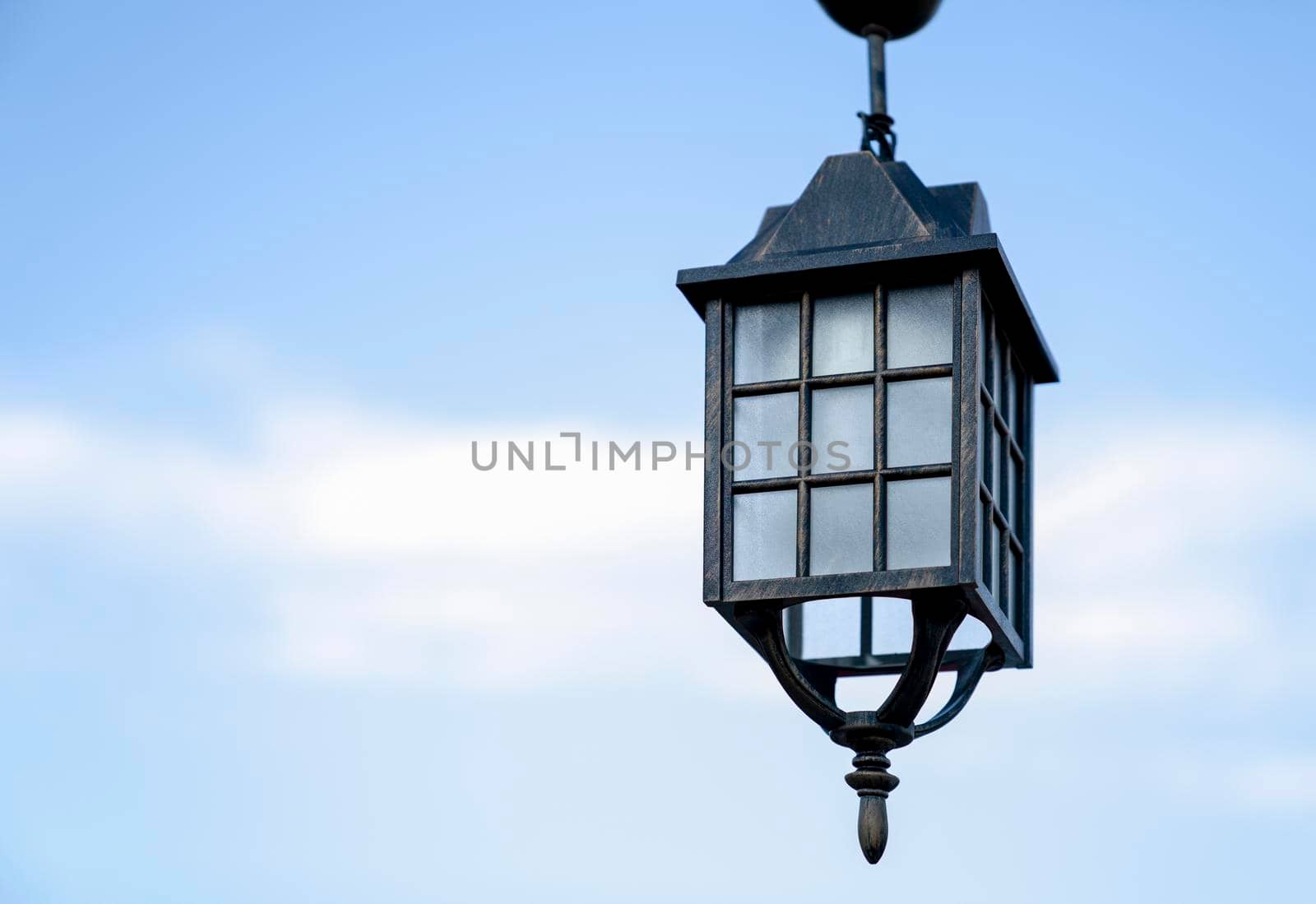 Ancient street lamp against blue sky, close up. Copy space.