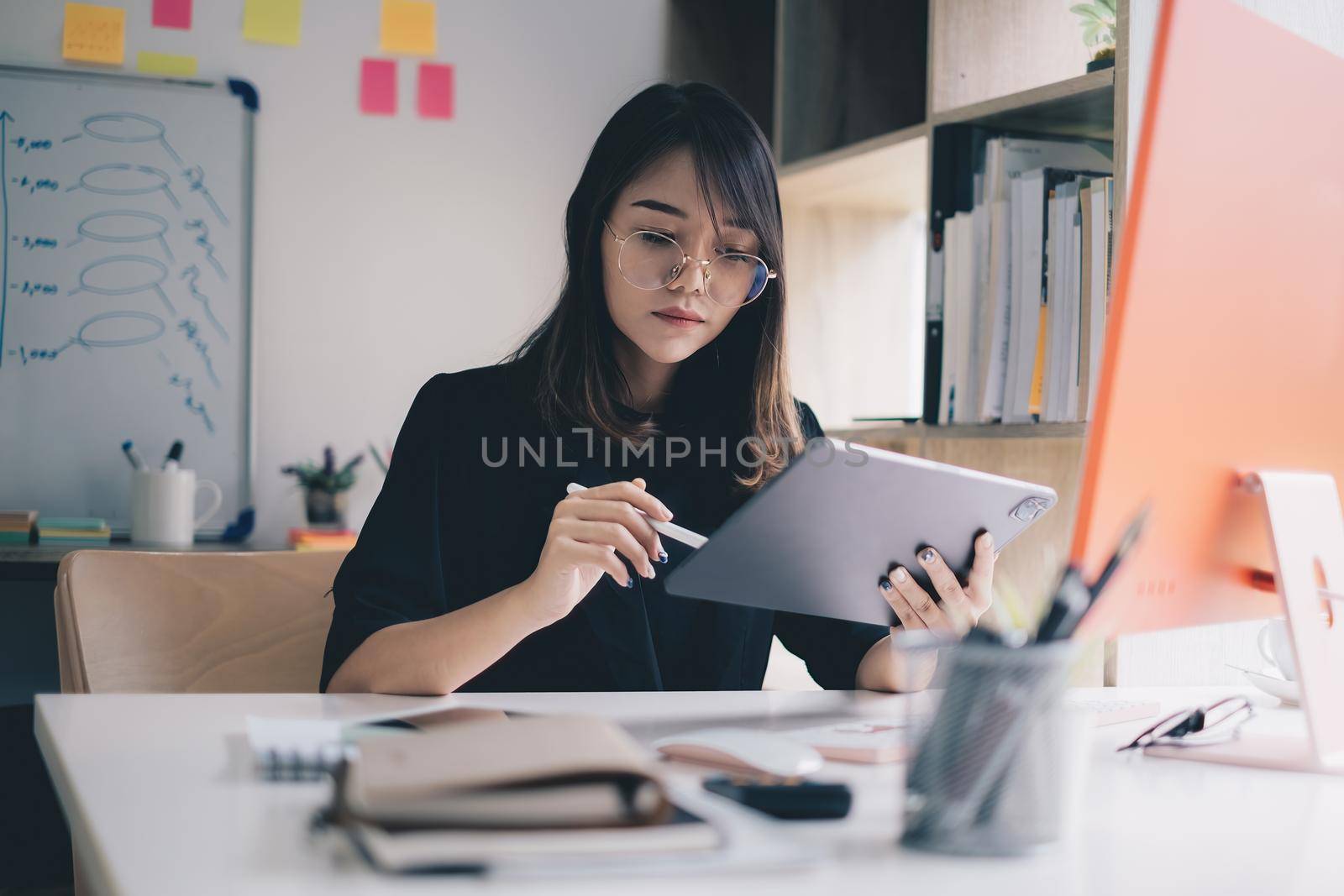 Successful trader or business woman wear eyeglasses working with charts and market reports on digital tablet. Financial concept by itchaznong