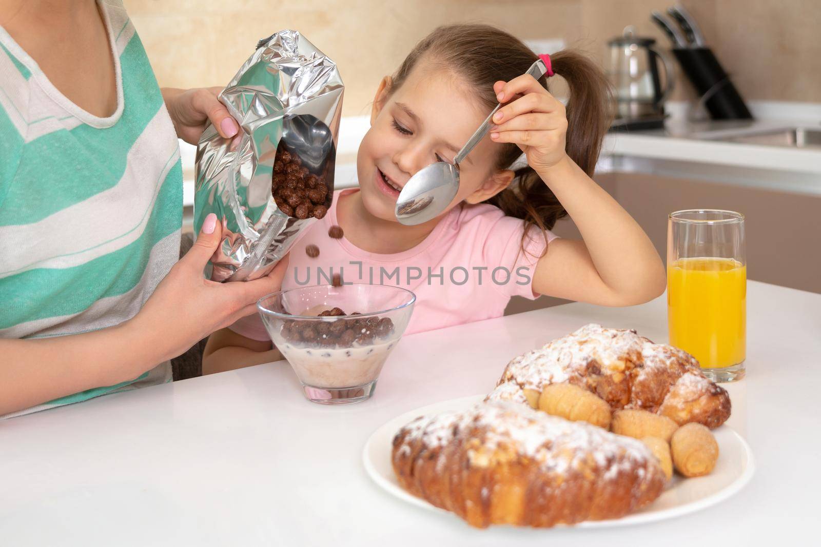 Mother serving breakfast to her two daughters at a table in kitchen