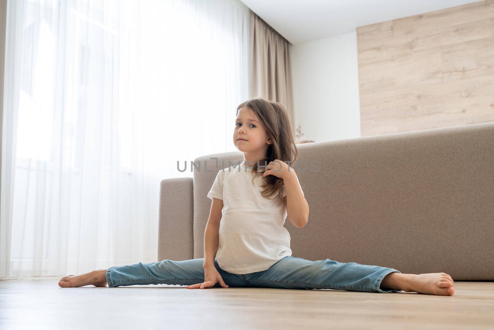 Little girl doing split in living room at home by Mariakray