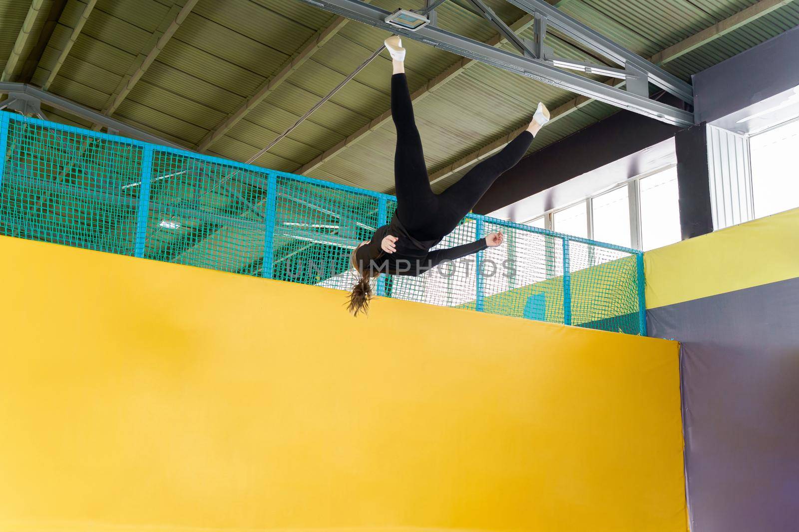 Young woman amateur acrobatic athlete jumping and exercising on a trampoline indoors