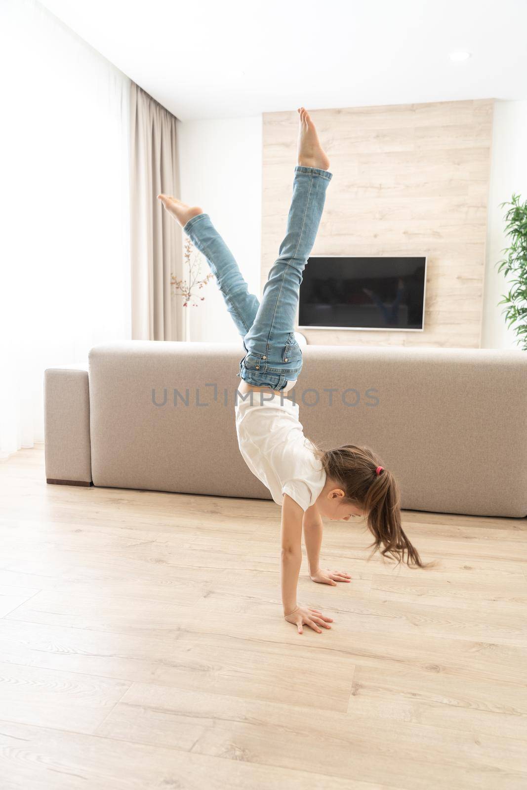 Girl walking upside down on her arms at home by Mariakray