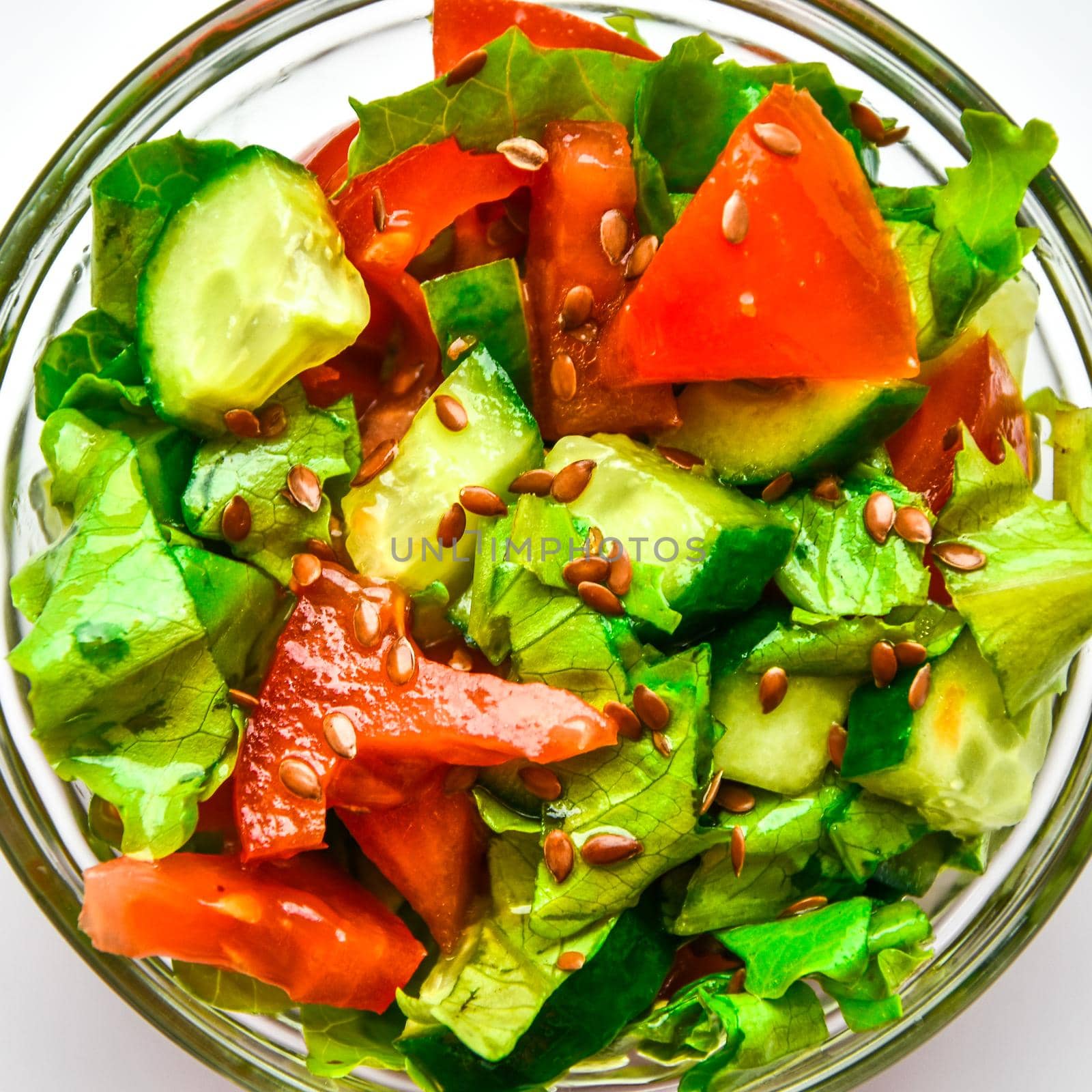 served plate with fresh salad from tomatoes, cucumbers, salad leaves and flax seeds isolated on white background, Top view, Copy space for text, Vegan diet food