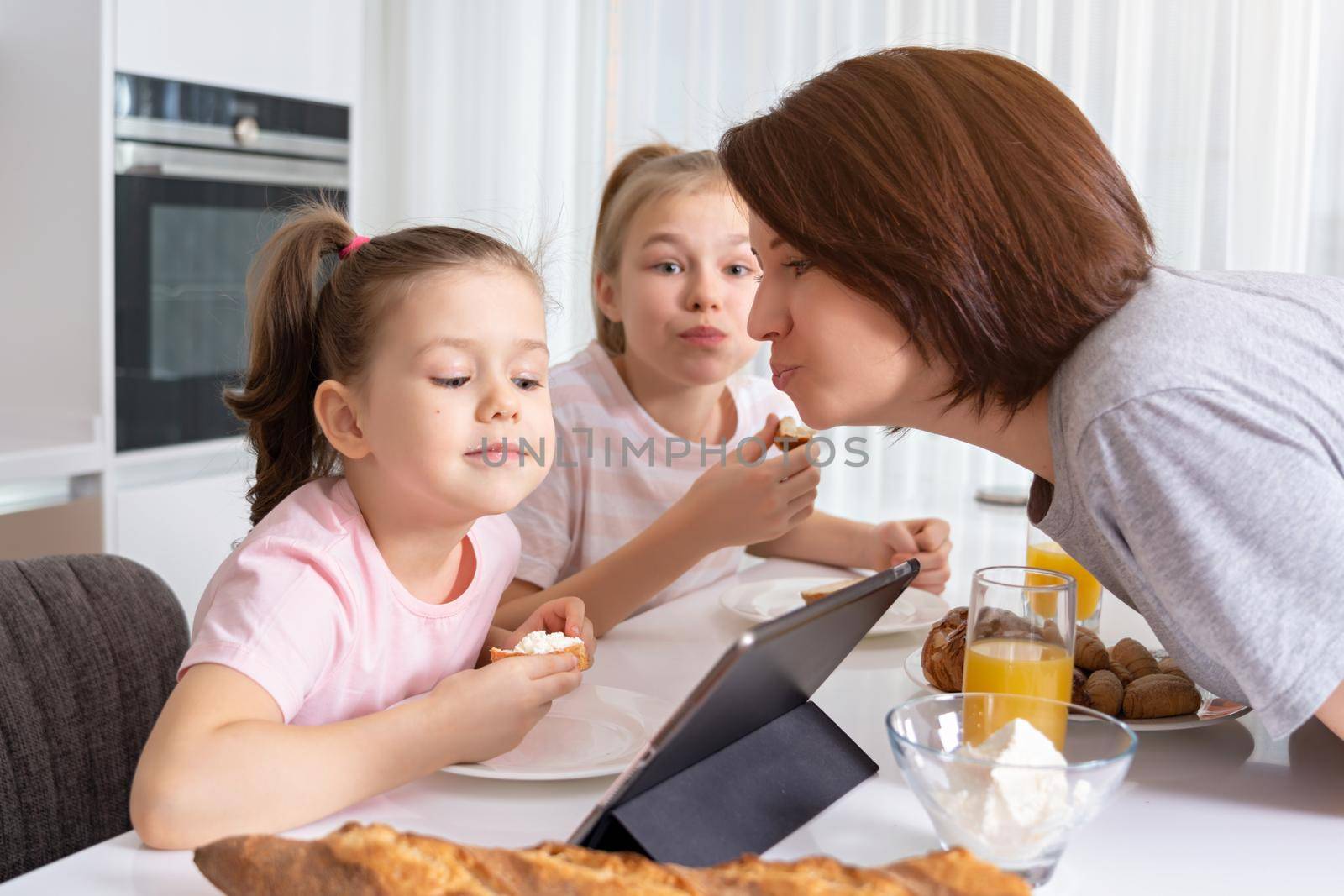 Mother trying to kiss daughter while having breakfast together