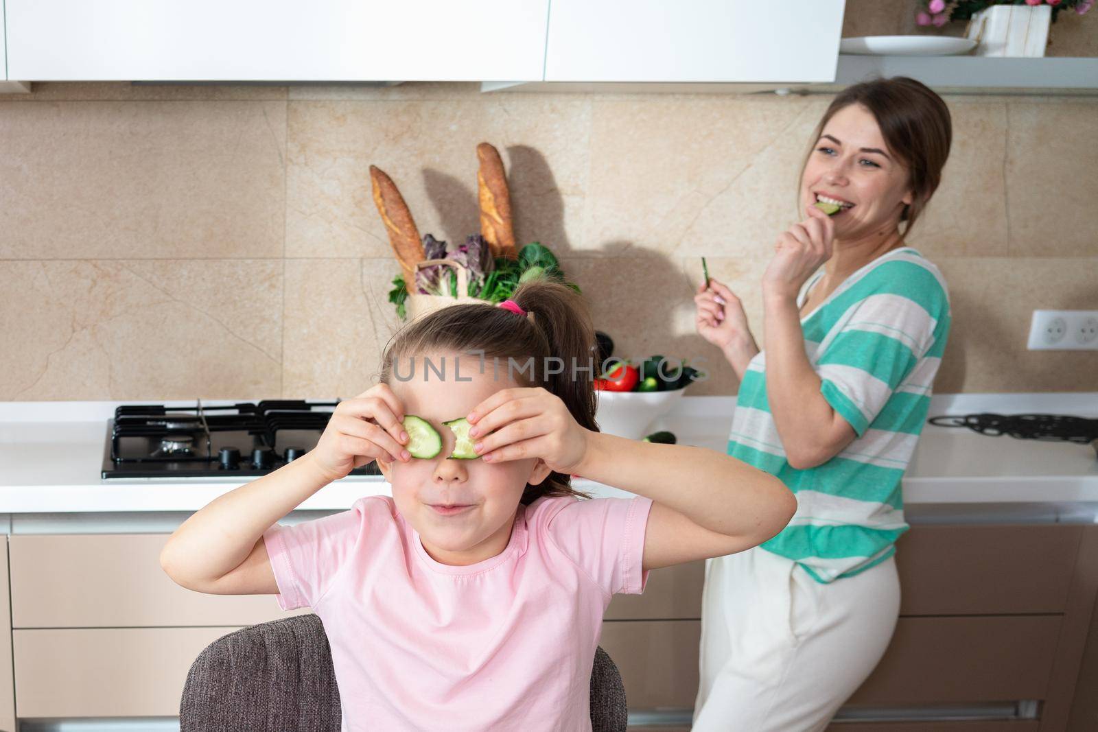 Happy young mother and daughter having fun in kitchen, happy single mother family concept by Mariakray