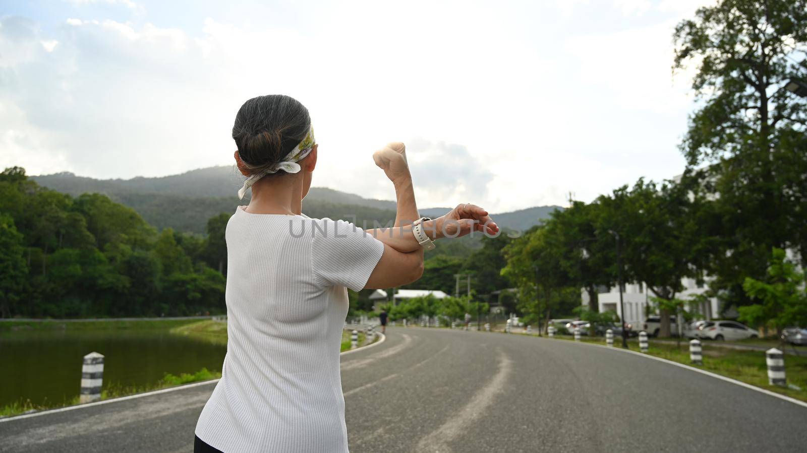 Active healthy middle aged woman stretching arm, warming up before morning workout. Healthy lifestyle, workout and wellness concept.
