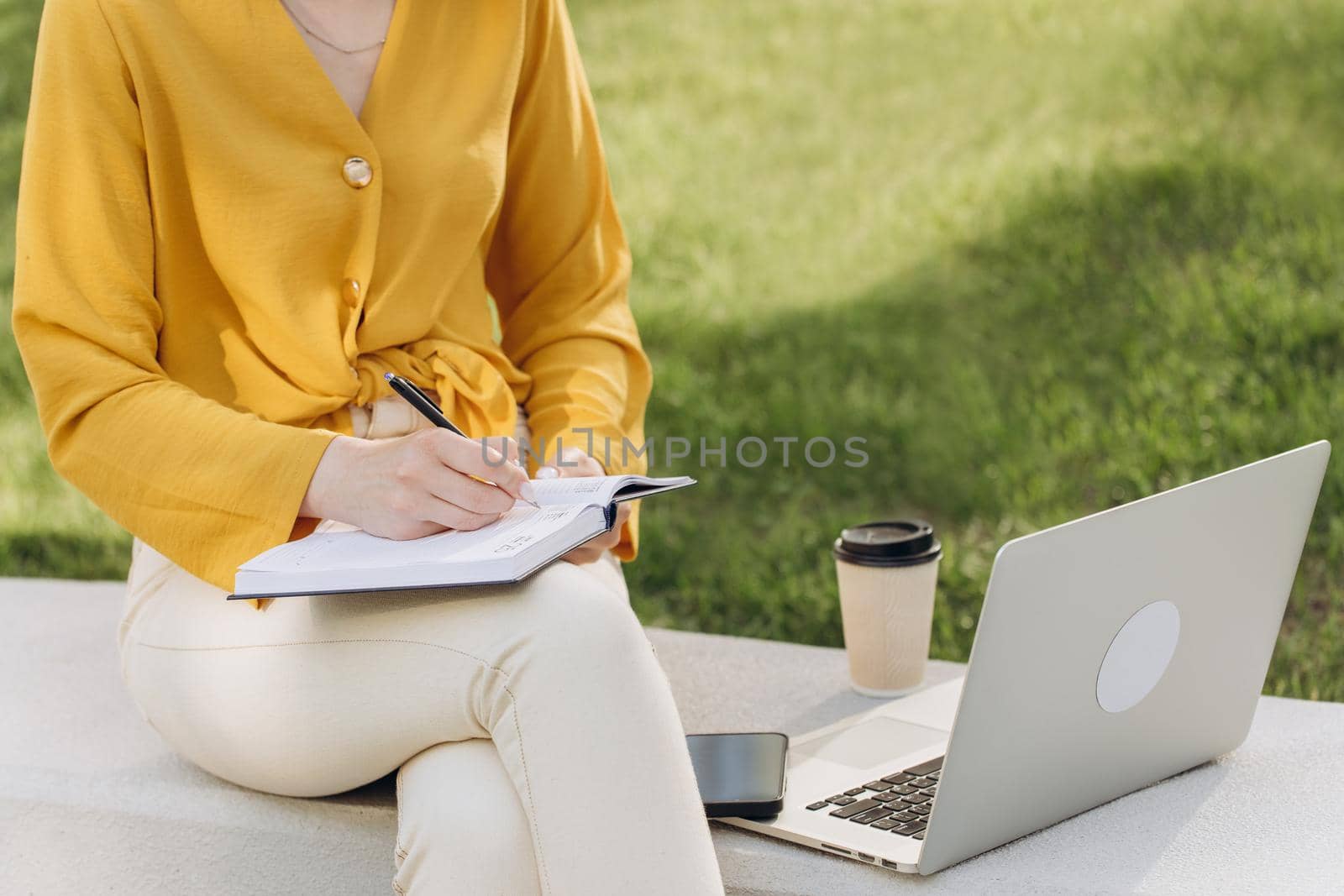 Closeup caucasian businesswoman hands making notes in notebook at workplace. Unknown female entrepreneur writing schedule in diary book. Unrecognizable business woman arms crossing text in notebook. by uflypro