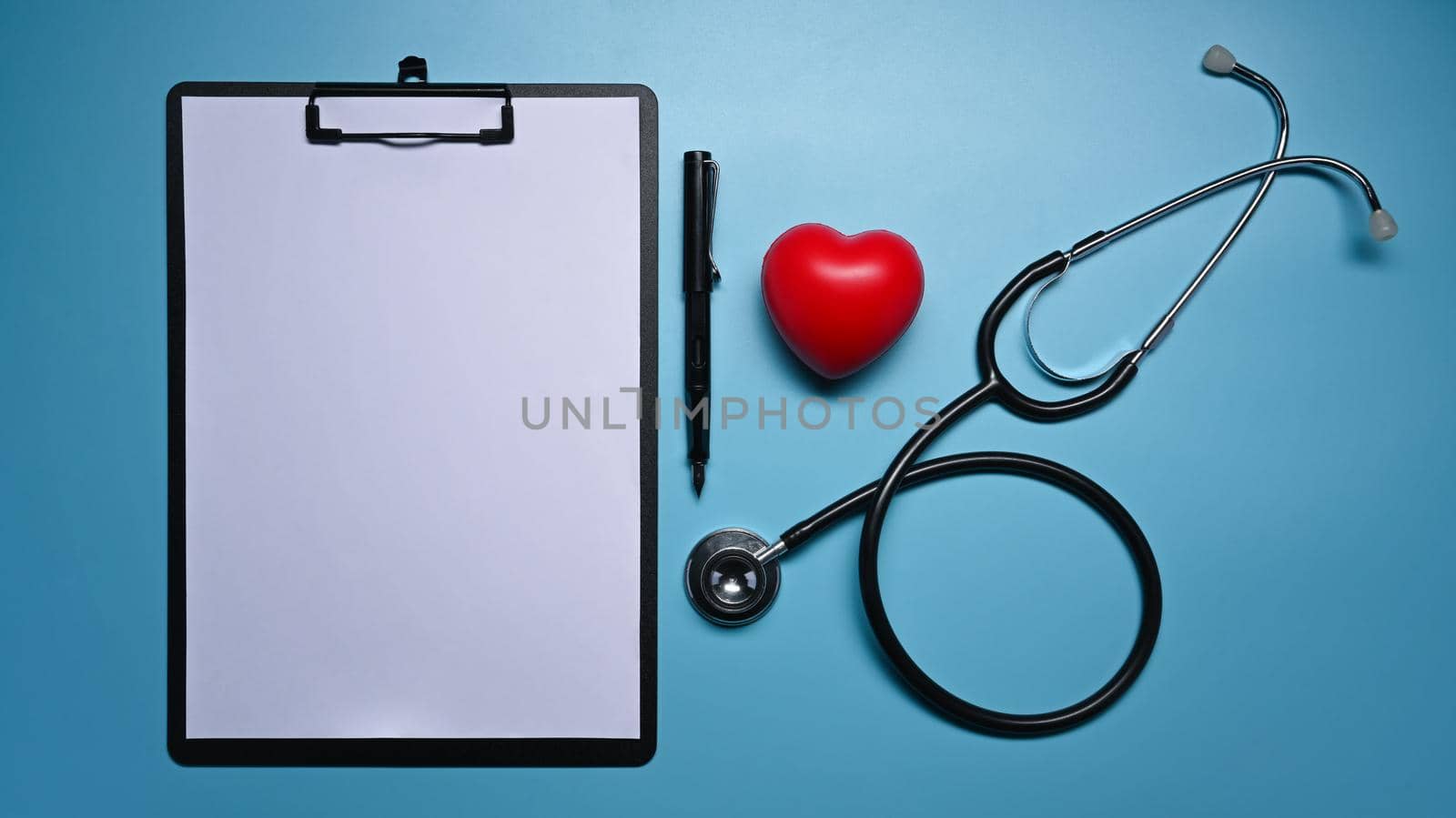 Clipboard, stethoscope and red heart on blue background. Healthcare and medical concept.