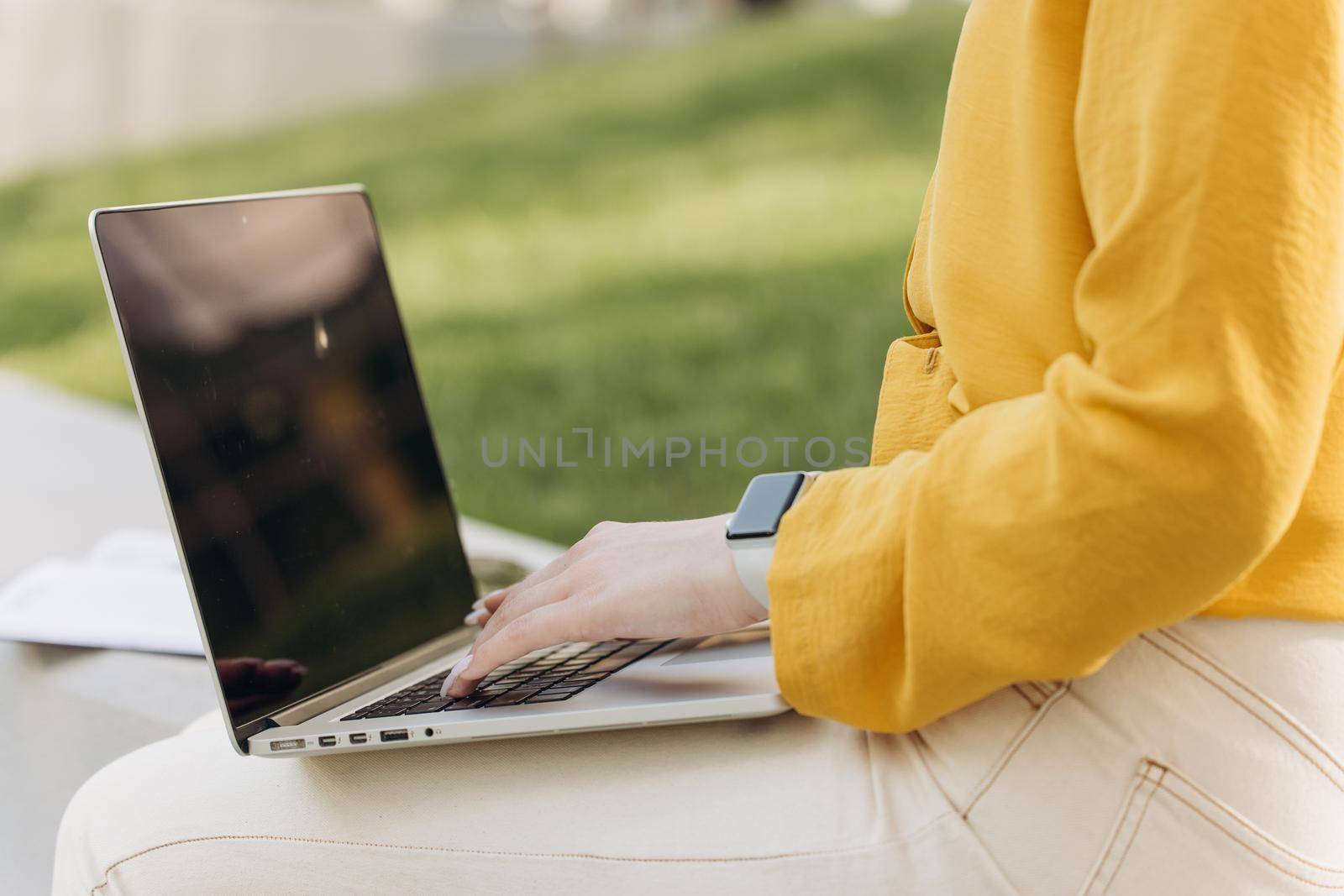 Businesswoman hands busy working on laptop computer for send emails and surf on a web browser. Hands of unrecognizable girl working outside at modern office on background. Concept of work at computer.