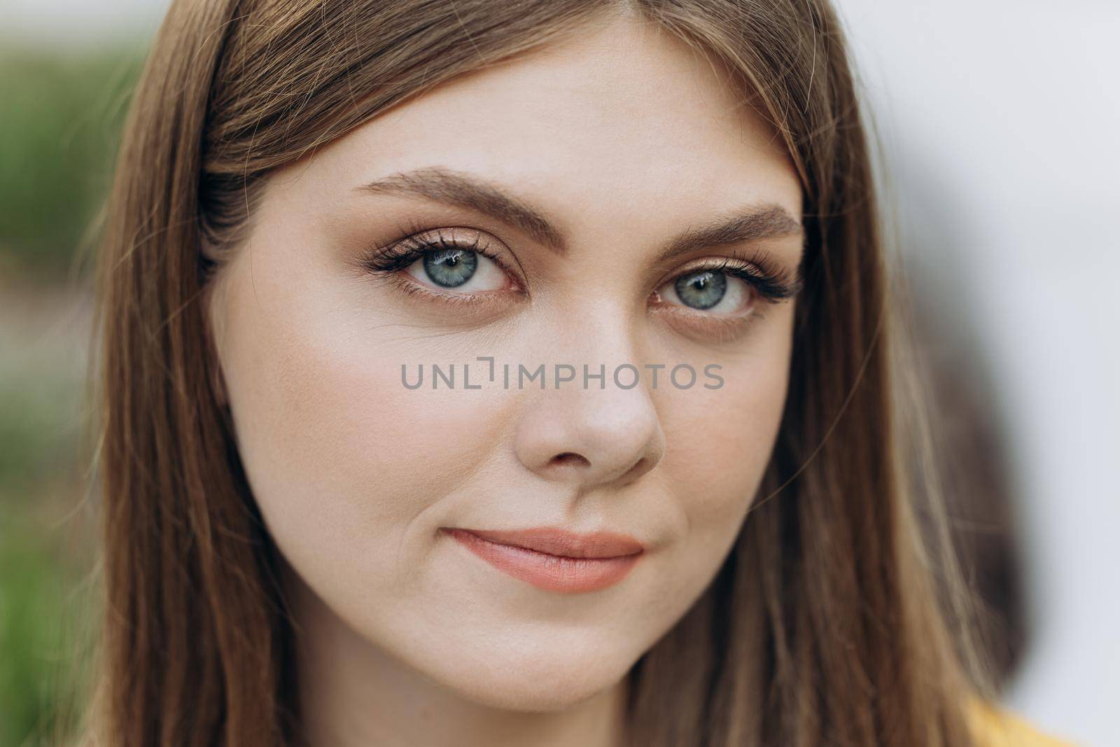 Close up of face young caucasian woman looking at camera serious attractive beautiful long hair stand on street city lifestyle summer girl city outdoors by uflypro
