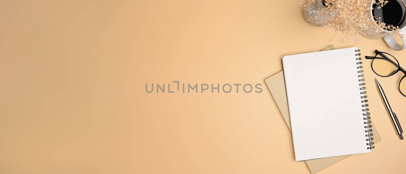 Top view notebook, eyeglasses and coffee cup on beige background. by prathanchorruangsak