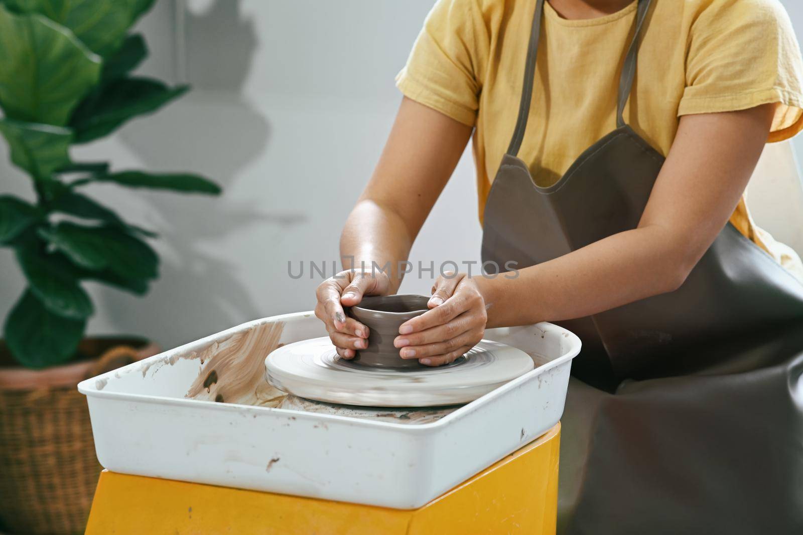 Concentrated asian woman making ceramic pot on potters wheel . Activity, handicraft, hobbies concept by prathanchorruangsak