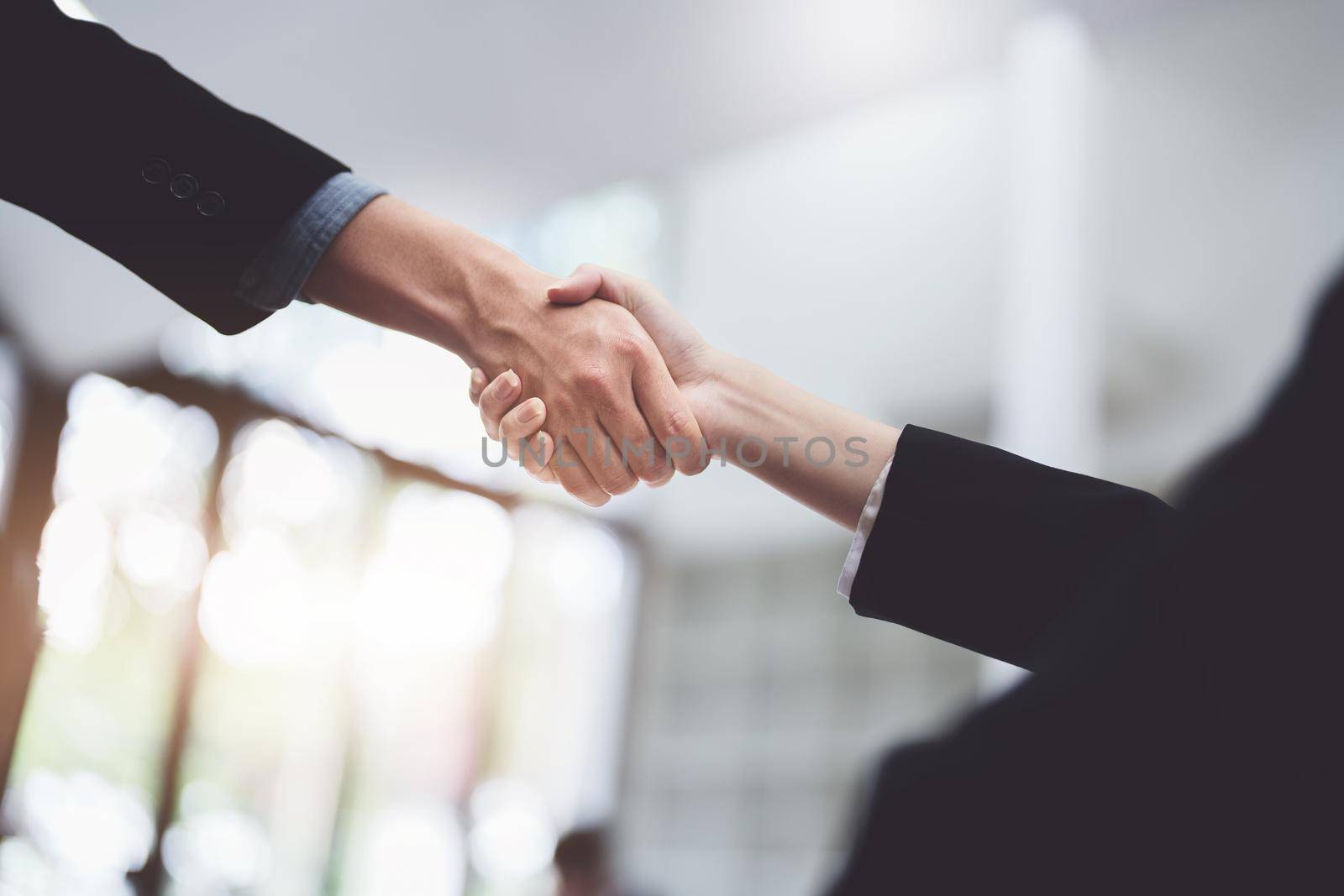 Asian entrepreneurs handshakes to congratulate the agreement between the two companies to enhance investment and financial strength. deal concept by Manastrong
