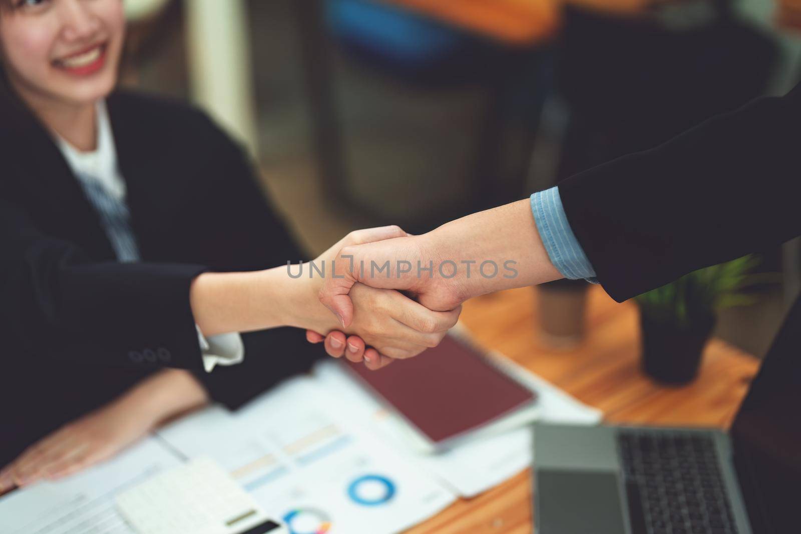 Asian entrepreneurs handshakes to congratulate the agreement between the two companies to enhance investment and financial strength. deal concept by Manastrong