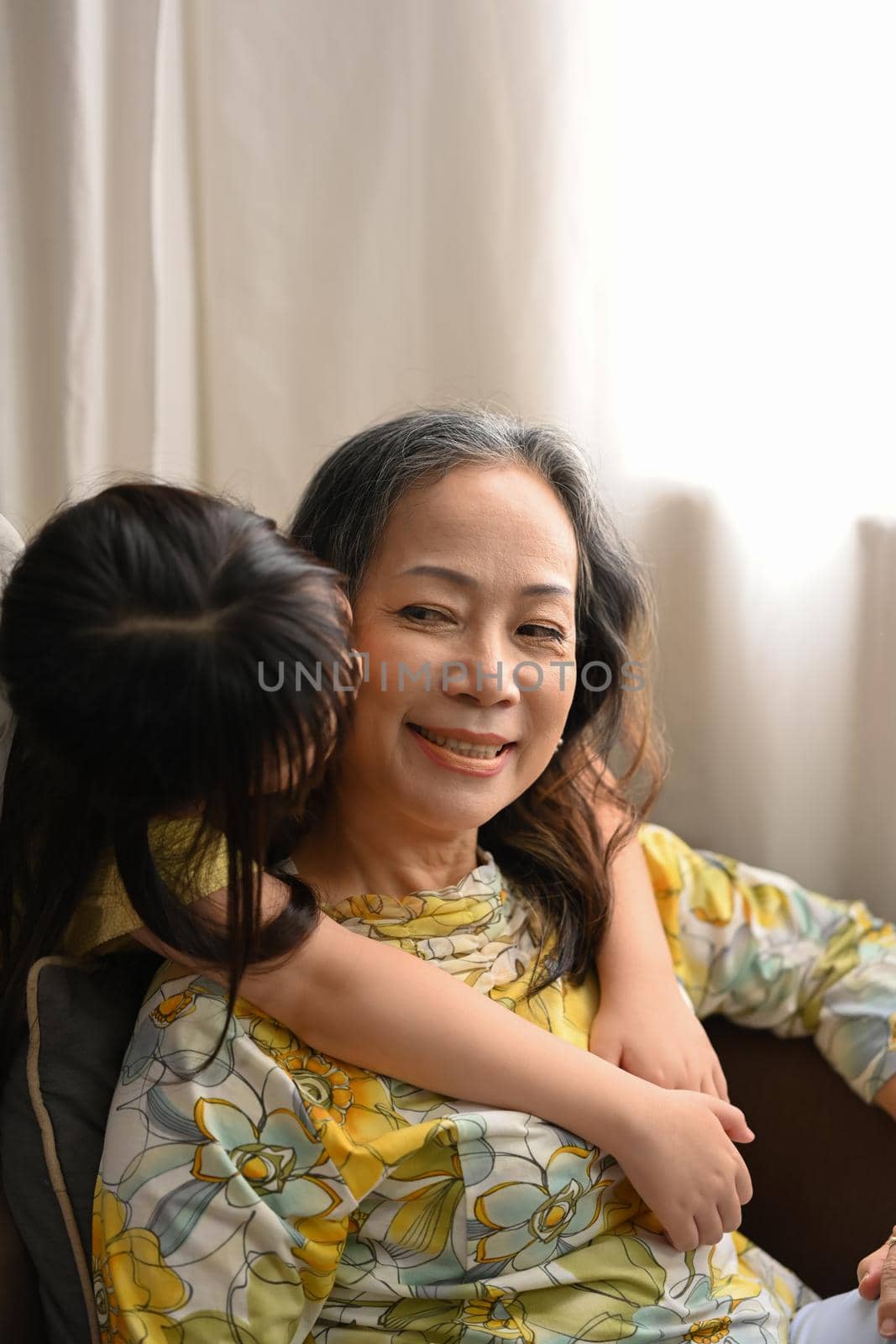 Little grandchild hugging and kissing on cheek her grandmother. Family and love concept.