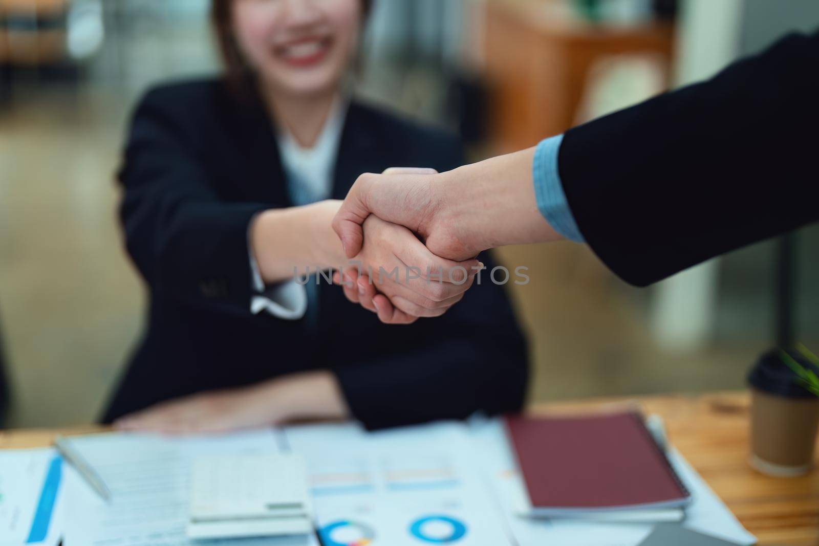 Asian entrepreneurs handshakes to congratulate the agreement between the two companies to enhance investment and financial strength. deal concept by Manastrong